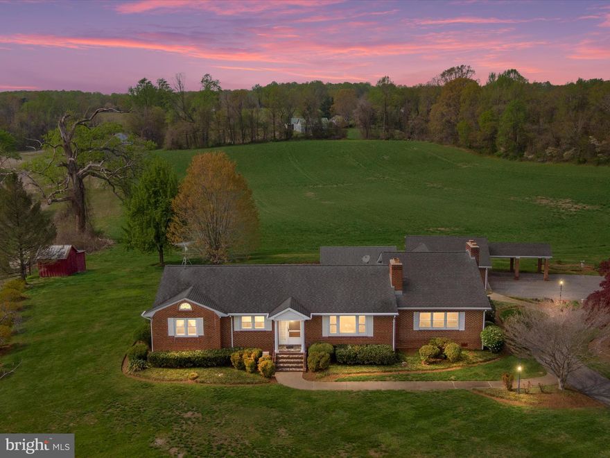 2ND CHANCE ALERT!  THE BEST VALUE IN  HARWOOD! Back on market after buyers change of plans, no fault of home or seller. Massive 75k Price Reduction! Priced well under appraised value! Rarely does a home with this much come along at such an accessible price!  Bring Mom & Dad, there's an in-law suite in the lower level!  Relax and enjoy this sprawling all-brick rancher nestled on a peaceful, private setting surrounded by gently rolling farmland and sweeping sunset views. Conveniently located near many commuter routes including Route 50 and Route 2 and just minutes from Annapolis!  You'll be delighted from the moment you pull up.  A circular driveway leads you through pastoral surroundings to a home that radiates appeal before you even step inside. With its classic brick exterior, graceful breezeway, and inviting entry, the approach sets a tone of privacy and character—welcoming you into a space that feels like home from the very first moment.  Inside, the main level features three spacious bedrooms and two full baths, solid hardwood floors, and a layout designed for both comfort & connection. The expansive great room with soaring ceilings, walls of windows, and a dramatic floor-to-ceiling stone fireplace is the heart of the home—an ideal space for entertaining or simply enjoying evenings with boundless views. A formal living room, complete with detailed trim and a beautiful marble hearth fireplace, offers an inviting space perfect for quiet mornings, conversations, or welcoming guests with classic charm. The kitchen and dining areas offer the perfect blend of comfort and function. The spacious kitchen features warm oak cabinetry, a center island, a breakfast bar, and generous counter space—ideal for meal prep, morning coffee, or gathering with family and friends. A large window over the sink frames beautiful views of the backyard, bringing in natural light and a connection to the outdoors. The kitchen opens directly to the great room, creating a welcoming flow that’s perfect for entertaining. Just off the kitchen, the traditional dining room is separate from the main living areas, offering an elegant space for formal meals or holiday gatherings. It also includes a unique built-in storage closet with shelves—perfect for storing fine china, serving pieces, or hosting essentials. Both spaces reflect the thoughtful layout of the home: functional, spacious, and full of opportunity to live—and host—with ease.  Downstairs, the fully finished lower level expands the living space significantly, offering two additional bedrooms, a full bath, and a massive family room with a wood stove and built-in shelving. With plenty of space for in-laws, multi-generational living, teen or guest quarters, a home-based business or even a separate rental suite, the lower level is set up ideally . There’s also a second full kitchen—once used as a canning kitchen currently complete with 2nd laundry area—offering the perfect setup for multi-generational living, guest quarters, or even a separate living space with its own private feel.  Outside, enjoy peaceful mornings or evenings watching the sunset under the covered stamped concrete patio overlooking acres and acres of picturesque farmland. The professionally designed landscape is gorgeous with mature trees, flowering shrubs, and even a little red shed out back—adding to the beauty of this one-of-a-kind property. The all brick construction extends beyond the home to include a one-car garage and a matching brick carport connected by a breezeway—ideal for additional parking, outdoor projects, or covered entertaining. The garage also offers exceptional storage with two separate storage rooms—one at the front and another at the back—perfect for tools, seasonal items, or a hobby space. The home is also complete with a whole-home generator and updated HVAC. Whether you’re looking for a peaceful forever home, a multi-generational retreat, or a place with great views, this is THE ONE!