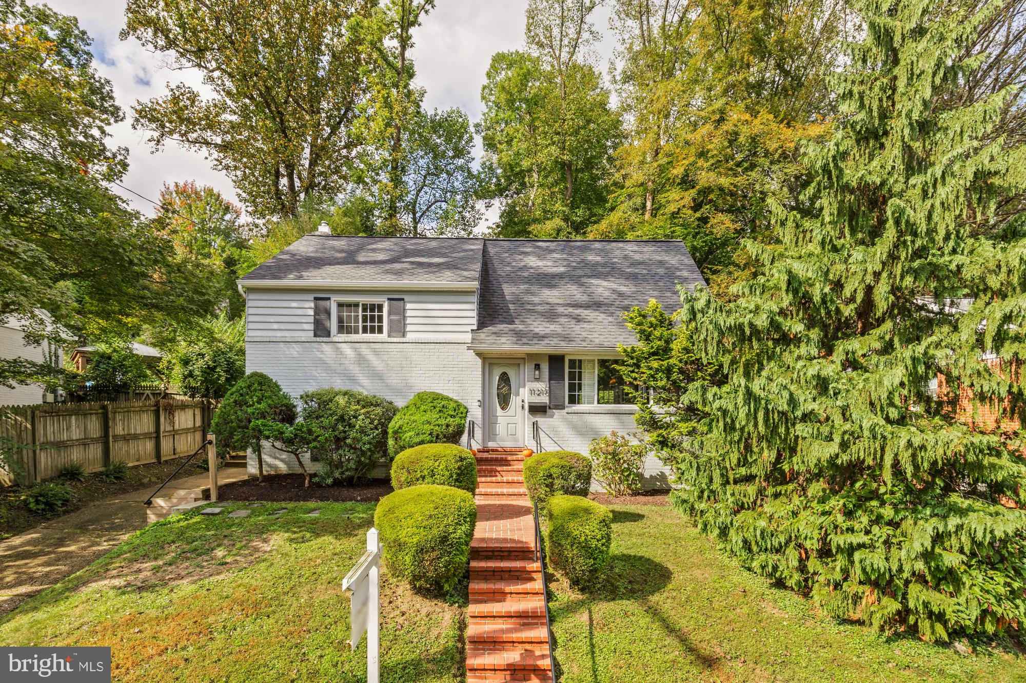 Welcome to 11216 Dewey Road, Rock Creek Palisades
Tucked away on one of the most private streets in Rock Creek Palisades, this mid-century Cape Cod is a perfect expression of what Standard Properties and the Daniels Brothers envisioned when they began developing the neighborhood in 1958- airy, light-filled homes on wooded lots that stay connected to nature.
Rock Creek Palisades was developed in the mid-20th century by Standard Properties, founded by the Daniel brothers — Clarke, Raleigh, and Cushing. Their vision was to design suburban communities that embraced natural beauty, with curving streets, wooded lots, and homes carefully positioned for light, privacy, and harmony with the landscape. Even the street names honor American history, commemorating World War II admirals — including Admiral George Dewey, for whom this road is named.
Set on a generous 19-acre lot this home offers 1,935 sq. ft. of finished living space and 2,375 sq. ft. total creating a rare combination of charm and functionality. Step through the front door and you’re greeted by natural light streaming through the large bay window, highlighting the living room’s gas fireplace and built-ins. The kitchen and dining area flow seamlessly to the screened-in porch — perfect for al fresco dinners or weekend coffee. Just off the kitchen, the sunken family room provides additional gathering space and connects to a laundry/mudroom and full bath.
One level down, you’ll find a flexible bonus room (currently staged as a bedroom) and 230 sq. ft. of storage space, complete with a second refrigerator. Upstairs, two bright bedrooms share an updated hall bath, while the top level is dedicated entirely to the primary suite — featuring a walk-in closet, en-suite bath, and 120 sq. ft. of attic storage
Outside, you are just 35 seconds from the Rock Creek Park trailhead, making daily walks and nature escapes effortless. This home offers a true sense of privacy and tranquility — the perfect retreat from city life, all while keeping you minutes from the heart of Kensington and Bethesda.