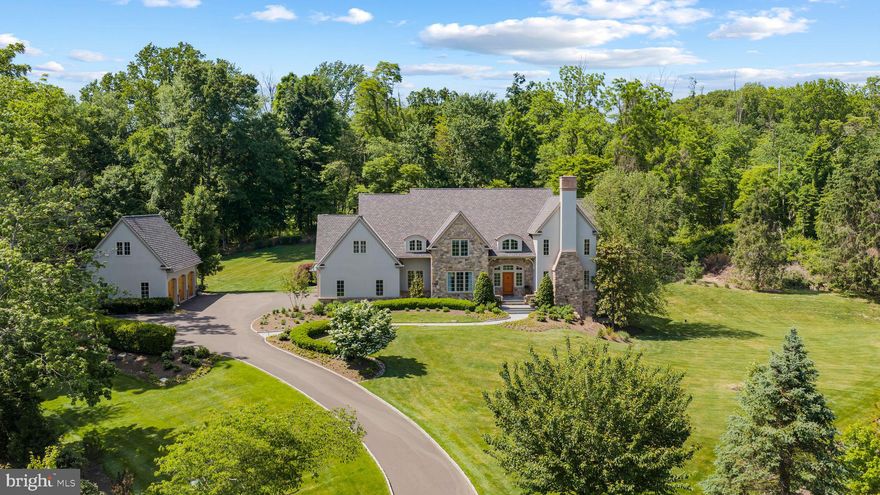 Tucked at the end of a private cul-de-sac within an intimate four-home enclave, this exceptional Zaveta-built custom estate is set on two beautifully landscaped acres just minutes from downtown Doylestown. Introduced by a winding Belgian block-lined driveway and surrounded by English garden-inspired grounds, the property blends architectural presence, sophisticated infrastructure, and refined craftsmanship across nearly 6,000 square feet of elevator-serviced living space. Built in 2015, the residence is defined by soaring ceilings, expansive windows, richly detailed interiors, and thoughtfully designed spaces that feel both elevated and exceptionally livable. A dramatic great room anchored by a floor-to-ceiling stone fireplace serves as the heart of the home, seamlessly connecting to a custom wet bar complete with wine storage, refrigerator drawers, and an ice maker. Nearby, the dining room transitions naturally into the updated gourmet kitchen, where quartzite countertops, paneled refrigeration, Thermador ovens, a concealed vent hood, and an oversized center island create an ideal setting for both entertaining and everyday living. Throughout the residence, upgraded Lutron lighting with high-CRI LED illumination, Sonos audio, four interior fireplaces, and extensive recessed lighting contribute to a warm yet contemporary atmosphere. The main level also features a spacious office with custom built-ins and a gas fireplace, along with a secondary gathering space offering flexibility for a media room, lounge, or additional entertaining area. A well-appointed mudroom and powder room are conveniently positioned nearby. The primary suite is privately situated on the main floor and offers a peaceful retreat with its own gas fireplace, generous walk-in closet, and a fully renovated Dolomite marble bath featuring radiant heated floors, a soaking tub, and an oversized walk-in shower. Upstairs, a second luxurious primary-style suite includes another spacious walk-in closet and marble bath with steam shower, while two additional bedrooms are thoughtfully arranged for family or guests. A uniquely designed fourth suite functions almost as its own private wing, complete with a sitting room, recreation or office space, powder room, and direct access to a private deck.
The walk-out lower level expands the home’s versatility with a spacious recreation room, private office, powder room, additional fireplace, and a fully equipped second wet bar with refrigerator, dishwasher, ice maker, and dual refrigerated drawers. Outdoors, multiple covered patios and gathering spaces overlook the impeccably maintained grounds, where mature trees and carefully curated landscaping create an exceptional sense of privacy. Additional features include full-property irrigation, 600-amp electric service, an attached three-car garage, a detached three-car garage ideal for collectors or hobbyists, a recently installed invisible fence, and a designer chicken coop enclosure. Ideally located near the boutiques, dining, and cultural attractions of downtown Doylestown - and just a short drive from New Hope and the surrounding river towns - this remarkable property offers a rare combination of privacy, scale, luxury, and convenience in one of Bucks County’s most desirable settings.