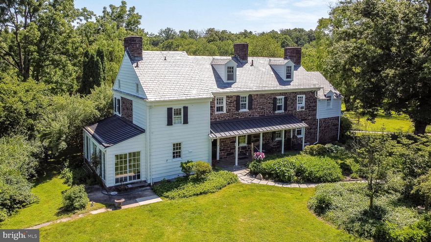 FIRE CREEK FARM. Two separate homes, a cathedral-like barn, a four-car garage/workshop and a gorgeous pool are the hallmarks of this one-of-a-kind property, with a provenance reaching back to the original William Penn Land Grant of 1681. The stone main house features five bedrooms, four and half baths, wide-width pumpkin pine floors throughout, and a multitude of unique and historic details, including a bee-hive wood oven, a hidden root cellar, a working antique well-pump, a spacious sunporch, a solarium overlooking the pool and much more. On the other end of the property, beyond the garage and barn, is the second home with its own drive, a brand-new deck overlooking a private garden, a spacious kitchen, four bedrooms and two full baths. It’s the perfect spot for guests, extended family, a caretaker, or even a reliable source of rental income. The pictures of the three-story barn do a much better job of capturing its grandeur than we could ever accomplish with words, but it’s good to remember that it’s been the setting for many a memorable party (including at least two weddings). A sizable portion has been carved out to create a fully insulated studio space, with soaring ceilings and incredible natural light. The barn’s lower level includes multiple stalls for farm animals and additional storage. Hidden on 10 lush acres with mature specimen trees, a stream, and access to a natural pond, the property is thoroughly private, yet it’s just ten minutes to New Hope, Newtown, Tyler State Park and nearby commuter routes to Philadelphia, Princeton, and New York City. A genuinely beautiful estate, and a rare opportunity to own a true piece of Bucks County history.