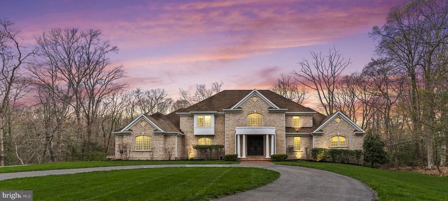 Welcome to an extraordinary offering in the highly coveted Ferry Landing Woods of North Calvert, where refined living meets everyday comfort in a community known for its charm and waterfront lifestyle.

From the moment you arrive, the circular driveway sets an impressive tone and invites you inside to discover what makes this home so special. The two story foyer and family room create an immediate sense of space and light, with large casement windows filling the home with natural sunlight. A graceful curved staircase and second level overlook add a classic architectural touch, while the built in library offers both beauty and function.

The kitchen is truly the heart of the home and designed for those who love to cook and gather. With dual sinks, upgraded granite countertops, an abundance of cabinetry, and an oversized pantry, it offers both style and practicality. Just off the kitchen, the screened porch provides the perfect setting for relaxed dinners or quiet mornings overlooking the private backyard.

The main level primary suite is spacious and inviting, offering a comfortable retreat with a well appointed bathroom featuring dual vanities, a soaking tub, separate shower, and a thoughtfully designed walk in closet. Upstairs, three generously sized bedrooms provide excellent accommodations, including one with a private ensuite and two connected by a Jack and Jill bath, each with their own vanity and private space. A large main level office offers flexibility and could easily serve as a sixth bedroom if needed.

The lower level opens up even more possibilities. Whether you envision an in law suite, entertainment space, or both, this level delivers with a full kitchen area, expansive open rooms, a media space with projector and screen, and a built in wet bar with granite countertops. A large bedroom and full bath make it ideal for guests or extended stays.

Out back, the home truly shines. The custom paver patio was designed with entertaining in mind and features a pergola, built in firepit, seating wall, and a wood fired pizza oven that brings everyone together. The fully fenced yard offers privacy and a peaceful setting that can be enjoyed throughout the year.

Additional features include dual zoned HVAC, a striking floor to ceiling stone fireplace, generous storage throughout, a spacious laundry room that doubles as a mudroom, and an EV charger.

Living in Ferry Landing Woods means enjoying access to the Patuxent River with a community boat launch, pier, and pavilion where neighbors gather for events and celebrations. It is a place where you can spend your days kayaking, paddleboarding, fishing, or simply enjoying time outdoors with family and friends. Its location in North Calvert offers the perfect balance of a quiet setting while still providing an easy commute to Andrews Air Force Base, the Pentagon, and Washington DC.

This home offers a rare combination of space, comfort, and lifestyle in one of the area’s most desirable communities. Once you step inside, you will want to see more.