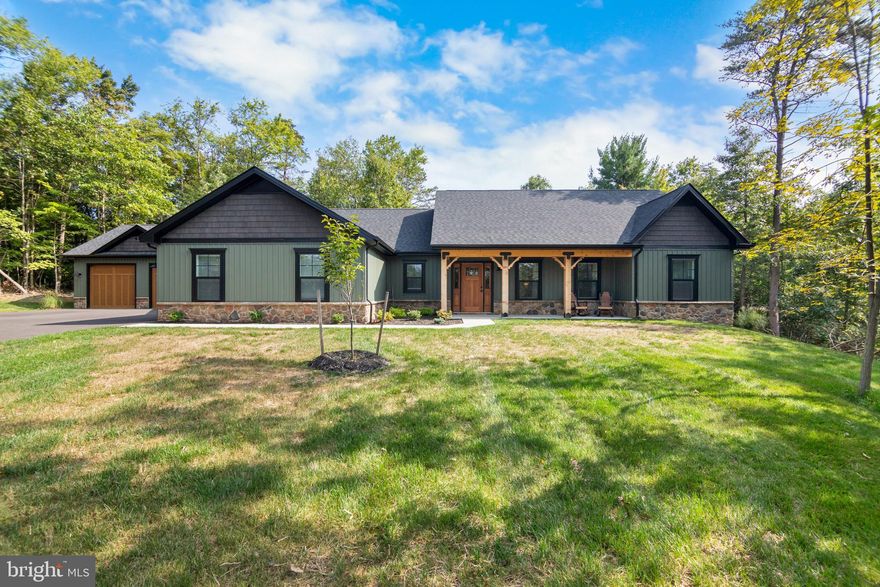 Welcome to your serene retreat on the outskirts of Hedgesville. Set on 2.5 wooded acres, this newly built ranch home blends modern style with rustic charm. As you approach, you'll notice the impressive wood accents that define its design. The property features both attached and detached two-car garages for ample storage. Inside, the open-concept layout seamlessly integrates the living room, kitchen, and dining area, enhanced by new LVP flooring throughout. The living room boasts high ceilings, adding to the spacious feel. The kitchen is equipped with stainless steel appliances, white granite countertops, and a generous center island. Off the dining room sit two spacious bedrooms which share a full bathroom. In addition, the primary bedroom features a walk-in closet and master suite. The master suite features a double vanity and a stand-up glass shower. Outside, the expansive covered patio offers an ideal spot for relaxation or entertaining. This pristine property is a must-see—schedule your showing today!