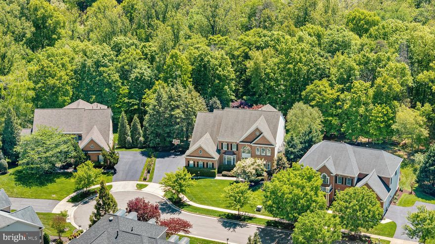 On the banks of scenic Goose Creek, this impressive estate of significant influence awaits in a highly exclusive cul de sac in the community of Lansdowne on the Potomac. A stately brick colonial home combined with a private pool on a premium lot all backing to mature trees for exceptional seclusion is simply unmatched for this community. Lush landscaping framed with stately colonial architecture as the home greets you with a dramatic double height foyer with sweeping stairs and art quality lighting. The entrance flows seamlessly across the formal dining room with butler’s pantry, private reading library, home office, sunroom and enlarged gathering room. Guests will be awestruck by sunlight beaming in through an abundance of views from the windows as this path will lead to the open concept chef’s kitchen. In the timeless chef inspired kitchen, create best-loved recipes with the help of professional grade Viking and Sub-Zero appliances. Guests and family alike will adore savory holiday meals in the dining room, and joyful brunches in the luxurious sunlit breakfast room. From the kitchen, a meticulously framed ceiling will guide and delight as you explore the 7,600+ sq. ft. home. Intimate conversations and splendid gatherings alike are yours to host within several irresistible living spaces, while the main level study provide privacy for remote work, you can also relax in the reading room during the evenings with a book. Beautiful detailed hardwood floors will escort you to the home’s second level where the grand entrance offers views of dewy mornings and the meticulous landscaping. In the evenings, spacious bedrooms and spa-like bathrooms allow family and guests to unwind. In the primary suite, choose to relax in the dual shower or with an evening of bubbles in the regal soaking tub. Afterwards, your sitting-room with a miniature tea/wine bar beckons you to continue plans of blissfully hiding away. A elegant primary retreat with a spacious custom closet featuring tailored shelving and an exclusive second story balcony with tranquil poolside views offer an easy escape from a busy day. There’s no shortage of entertainment and pampering as the home offers movie nights in the theater, a lower level parlor, wine-tasting bar, home gym, crafts/hobby area, sports viewing room, pool/ping-pong table room and featuring a floor to ceiling cedar-lined storage room to store designer luxury goods. A lower level bedroom can be ideal for extended guests. As you approach the exit to the garage, an expanded mudroom with ample shelving for week long activities leads to a main level deluxe laundry room, complete with a concierge style high end steam closet for dry cleaner quality care for delicate clothing. Outside, a 3 car side load garage ensures effortless daily access and abundant space for vehicles and storage, combining convenience with refined functionality. Treat your guests to sunny afternoons by the pool and moonlit evenings near your custom outdoor wood burning fireplace. The residence features a sophisticated, multi-tiered surround sound system integrated throughout both the interior living spaces and the exterior pool area, delivering an exceptional audio experience designed for elevated entertaining. As a member of the community, you’ll enjoy access to the exclusive Potomac Club, which offers swimming, tennis, billiards, gym membership, and event space. In addition, membership is available at the nearby Lansdowne Resort, which offers golf, spa services, and fine dining. Refresh your mood and connect to nature via the area’s numerous hiking trails, or choose to go boating and fishing on the Potomac River or Goose Creek. Nearby historic downtown Leesburg offers posh farm-to-fork restaurants, boutique shopping, and town festivals. Further afield, Washington D.C. will entertain with urban flair, and nearby Dulles International Airport awaits to transport you anywhere in the world!
