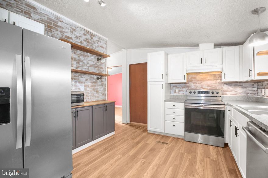 The smell of fresh coffee drifts through an airy kitchen as sunlight spills across refurbished wood shelving and a brick backsplash, bouncing softly off sleek stainless appliances. A quiet morning unfolds just beyond the windows—five private acres stretching out beneath mature trees, tucked near the end of a non-thru street. Peaceful, but never isolated.

Inside, 1,250 square feet of thoughtful updates capture attention immediately: exposed beams draw the eye toward vaulted ceilings, a stylish feature wall anchors the family room, and wide-plank wood laminate flooring flows throughout with warm, cohesive character. Every detail feels intentional, right down to the Smart House upgrades—voice-controlled smart plugs throughout the interior and Blink Security floodlights positioned at the front and rear, bringing both convenience and peace of mind.

The kitchen wasn’t just updated—it was reimagined. Clean lines in white cabinetry, a modern layout with updated countertops, and handcrafted open shelving offer personality as well as function. Both bathrooms heighten the design aesthetic, with fresh tile, contemporary vanities, and a new walk-in shower in the ensuite.

Comfort extends to the essentials: a new well pump (2023), an expanded front deck (2021), and a newer roof (2017). Step outside and the lifestyle unfolds even further. A pair of versatile sheds hold tools, equipment, or hobbies. A chicken coop offers a chance to collect your own morning eggs. The carport keeps vehicles protected, while the broad, usable acreage boasts cherry, peach, and pear trees and invites gardens, orchard plans, weekend bonfires, and small-scale homesteading. With no HOA, the land here belongs fully to those who call it home.

A retreat that allows life to slow down when needed, yet sits surprisingly close to shopping, restaurants, and major highway access. Updated, turnkey, and ready for the lifestyle you choose to build upon it.