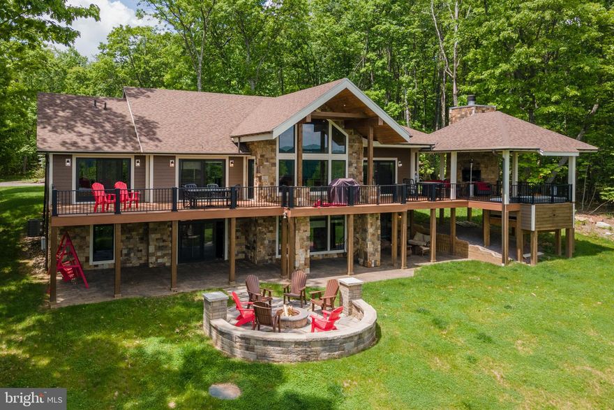 Stunning Don Nemith Build in Deep Creek Highlands – This luxury Mountaintop Oasis is perched hillside overlooking Deep Creek Lake and features two stories of glass to let in the light and mountain/lake views, a sprawling back deck with covered outdoor fireplace, and built-in hot tub, stone fire-pit patio and top to bottom high-end finishes throughout! Two primary Bedrooms on the main level with fully tiled showers, double bowl vanities, and balcony access to the back deck. Open-concept living with a stacked stone fireplace, wet bar, and timber accents in the great room. Gourmet modern kitchen with stainless appliances, stone counters, and bar top seating. Three more beds and baths downstairs adjacent to the 2nd living room, game room, bar, and fully equipped gym! The fully finished basement walks out to a stamped concrete patio with additional outdoor living space. If you’re looking for the perfect blend of rustic mountain living with luxury modern comfort, “Lookout Lodge” has everything you need. Call today for details!
