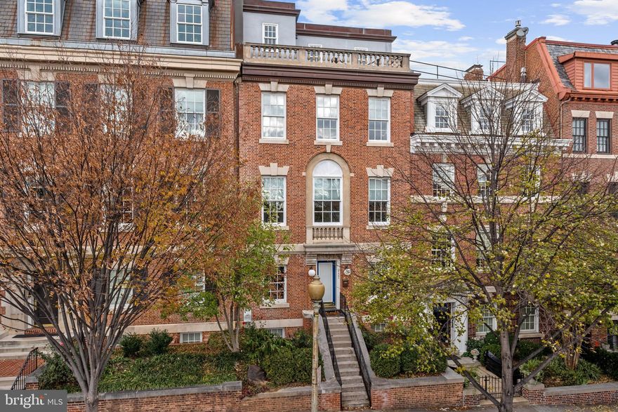 This quintessential brick row house is ideally located in the highly desirable Kalorama neighborhood. The grand residence was originally constructed in 2003 and has been meticulously maintained. It is south-facing and set off the street, capturing an abundance of natural sunlight throughout the entire home. This spectacular house features generously-proportioned rooms on five finished levels, providing the perfect space for formal entertaining and comfortable family living. The traditional façade has wonderful curb appeal with beautiful front landscaping and an iron rail fence to the entryway. The main level features exceptional entertaining rooms including a gracious front living room with a gas fireplace and an adjoining formal dining room. The updated eat-in kitchen is well-appointed with a large center island, stainless steel appliances, and abundant cabinetry storage. There are four large windows with custom plantation shutters and an exterior door to the rear parking pad. There is also the added convenience of a nearby powder room on this floor. The second level features two spacious bedrooms and bathrooms, including the luxurious primary suite. The primary bedroom has three oversized south-facing windows, a lovely gas fireplace, generous walk-in closet, and a marble en-suite bathroom with a skylight, dual vanities, a frameless glass shower, and jacuzzi tub. The second bedroom on this floor is also sizable and en-suite and offers two large windows with transoms and Juliet balconies. The third floor has an additional bedroom suite that could also act as a casual entertaining room. There are three south-facing windows, a fireplace, and an en-suite bathroom with dual vanities, a frameless glass shower, and a jacuzzi tub. The room is conveniently located near the impressive rear terrace with iron rail detail.  The top floor has an additional bedroom suite with a full bathroom and a lovely south-facing front balcony overlooking Kalorama and the Washington Monument. The lower level features a family room with built-ins, a laundry room with storage, a powder room, and an abundance of additional storage space. There is also two-car gated secure parking.