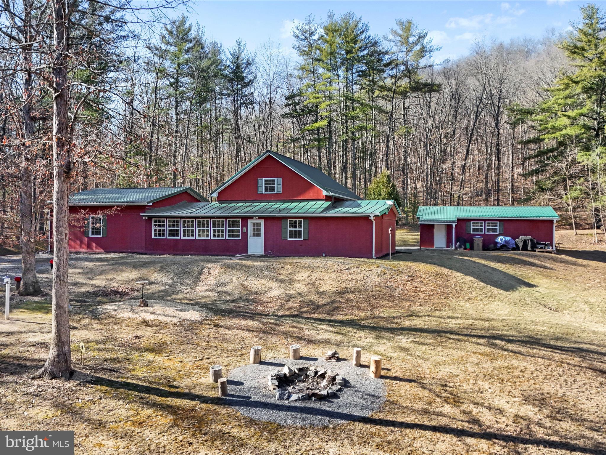 An easy day trip from the hustle and bustle of the city, this charming spacious home sits on over 5 acres with its own spring fed pond. To start, you enter the home in the sunlight finished front foyer that has lovely french doors that take you into the main dining area that looks into the kitchen. The vaulted ceilings create a space that is inviting and excellent for family dinners or entertaining friends and family. The wood floors throughout the main level and granite counter tops in the kitchen are appreciated high end finishes. The master bedroom with a spacious walk-in closet and en-suite bathroom and laundry room are conveniently located on the main level along with two additional bedrooms and an additional full bathroom. There is a fourth bedroom tucked away on the second level. As you walk past the kitchen, you will find another set of french doors that take you into the finished sunroom at the back of the home. The sunroom has a multitude of windows to enjoy the wildlife playing in the backyard. Keep your eyes open for the spunky squirrels and darting deer that often frequent the property. As you continue through the finished sunroom corridor, you will then enter into the large living room with high ceilings that boasts large windows to catch the view on the back, side and front of the home. The living room has a butler's pantry perfect for coffee lovers! The detached garage has bonus storage space and a workbench. If you seek the beach and lake, take a short trip to the private community lake and recreation area! There you will find a picnic pavilion, a small dock and beach to soak up the fresh air and sunlight. The home has had many upgrades recently to include the HVAC system and water filtration system. The roof is as good as you can get being metal! Come and see this gem in the WV mountains.