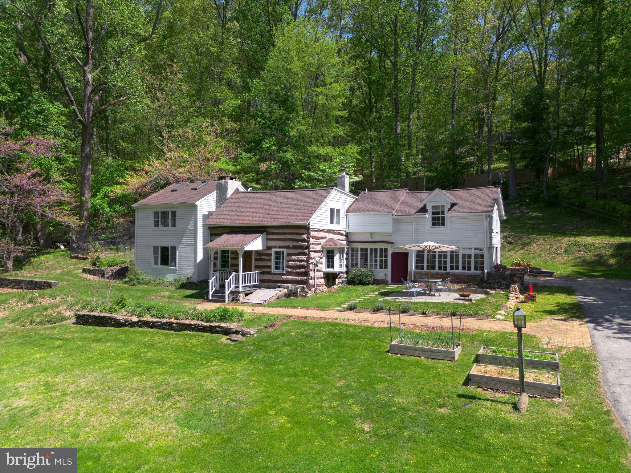 Tucked away on just over an acre in Wayne, this hidden gem is believed to be Montgomery County’s oldest continuously lived-in home, dating back to 1648. But don’t let the age fool you—this one-of-a-kind residence has been thoughtfully updated for today’s lifestyle while preserving its rich history and undeniable charm.
Step inside the original log cabin and you’re instantly transported. The heart of the home is a cozy, character-filled living room anchored by a massive stone fireplace, exposed beams, and wide-plank floors. Sunlight filters through storm-protected windows, casting a warm glow over the room’s beautifully preserved textures and details. Just beyond, the welcoming entry hall—with its vintage sconces and decorative fireplace—feels like stepping into a simpler, more elegant time.
Through the glass-paneled door, a magical sun porch awaits. With its flagstone floor, stone half-walls, and wraparound windows, it’s the perfect spot for morning coffee, casual dinners, or evenings strung with fairy lights and filled with laughter.
The bright, updated kitchen is as functional as it is charming. Crisp white cabinetry, dark granite counters, stainless steel appliances, and a beadboard ceiling are complemented by direct access to the rear deck—ideal for grilling or dining under the stars. A cozy bar nook, cookbook shelves, and coffee station add personality and ease.
Flowing from the kitchen, a light-filled dining and family room offers a casual gathering space with French doors to the backyard and wood floors that echo the home’s rustic roots.
Upstairs, five bedrooms and three full baths provide flexibility and comfort. The vaulted primary suite feels like a peaceful retreat, with two full walls of windows, skylights, and tranquil views of the lush grounds. A large walk-in closet and modern en-suite bath complete the space. Two additional bedrooms share a cheerful Jack-and-Jill bath, and a fourth bedroom and fifth bedroom —classic and cozy—are served by a hall bath with a claw-foot tub and vintage charm.
Outside, a spacious deck overlooks stone-walled gardens and a rolling, private lawn ringed by mature trees. Thoughtful improvements—like new retaining walls, updated drainage, and deer fencing—make it as practical as it is peaceful.
Recent upgrades include mini-split HVAC, partial roof replacement (2023), chimney repointing with wood stove insert, extensive log cabin restoration, removal of knob-and-tube wiring, EV charger, restored and new hardwood floors, and even historic details like salvaged switchplates from Do Do Hamilton’s home.
With easy access to Center City, King of Prussia, major routes, and the train station—and located in the Upper Merion School District—Cherry Garth is more than a home. It’s a living piece of history, lovingly cared for and ready for its next chapter.
If you’ve ever dreamed of a home with a story to tell—this is it.