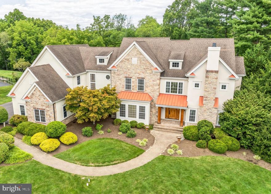 Nestled in the prestigious community of Afton Crest, this extraordinary 5-bedroom home on 4.6 meticulously maintained acres offers a perfect blend of luxury, comfort, & modern conveniences. From the moment you arrive, the home's impressive stone façade, accented by charming tin roofs & a welcoming brick paver walkway, sets the tone for the elegance found within. Step inside, where warmth radiates from the hardwood floors that stretch through the main level, enhanced by radiant heating on both the first & second floors. The foyer's crown molding & wainscoting further elevate the space. The living room, w/ its tray ceiling, intricate moldings, & gas fireplace, invites you to relax in a sophisticated setting. A convenient dry bar adds an element of class for entertaining. Adjacent, the formal dining room continues the theme of refined elegance w/ wood floors, a tray ceiling, detailed chair rail, creating the perfect space for gatherings. At the heart of the home lies a gourmet kitchen, a culinary masterpiece designed for both function and beauty. Two spacious islands with sinks, Thermador appliances, dual dishwashers, a wine cooler, & a built-in Sub-Zero refrigerator make this space ideal for any chef. Soapstone countertops, a tile backsplash, & wood beams add charm, while built-in ceiling speakers set the mood. Whether preparing meals or hosting casual get-togethers, the kitchen’s thoughtful layout offers both style and efficiency. The adjoining sunroom, bathed in natural light from skylights and sliders, seamlessly connects to the expansive deck for effortless indoor-outdoor living, perfect for both intimate moments & larger gatherings. The family room is both cozy & grand, with vaulted ceilings, exposed beams, built-in bookshelves, and gleaming hardwood floors. This inviting space is ideal for relaxing evenings or lively social gatherings, blending comfort w/ elegance. Everyday functionality is enhanced by a laundry room w/ abundant counter space & cabinetry plus a convenient laundry chute, & a mudroom w/ custom built-in for easy organization. Two well-appointed powder rooms on the main floor add convenience for guests. Upstairs, the primary suite is a true retreat, w/ hardwood floors, & a private sitting room that offers a serene escape. The spa-like en-suite bathroom features a double vanity, a spacious glass block shower w/ a bench, & built-in ceiling speakers to create a soothing ambiance. Bedroom #2 serves as a princess suite w/ an en-suite bathroom & walk-in closet, while Bedrooms #3 & #4 also offer private en-suite bathrooms for ultimate comfort & privacy. Bedroom #5, located near a well-appointed hall bathroom, offers flexibility for various uses, whether as a guest room, office, or creative space. The second floor also features a versatile loft area, perfect for a cozy reading nook or additional living space. The fully finished walkout basement is an entertainer’s paradise. A 130 sq. ft. keypad-secured wine cellar, a built-in wet bar, & a theater room w/ stadium seating, surround sound, & ambient wall sconces create the perfect setting for movie nights. The basement also includes a spacious game room, a well-equipped gym, & a luxurious full bathroom w/ a sauna & steam shower for ultimate relaxation after a workout or a long day. Outside, your private oasis awaits. The composite deck provides ample space for outdoor dining & lounging, while the stone patio, complete w/ a built-in wood-burning fireplace, sets the stage for cozy evenings under the stars. A hot tub adds the finishing touch to this serene outdoor space, offering a perfect spot to unwind & enjoy the tranquility of your surroundings. With a whole-house generator ensuring continuous comfort & the peace of mind that comes with being in the sought-after Pennsbury School District, this home is a rare find. The combination of luxurious details, modern amenities, & a tranquil setting make this property a truly exceptional place to call home.