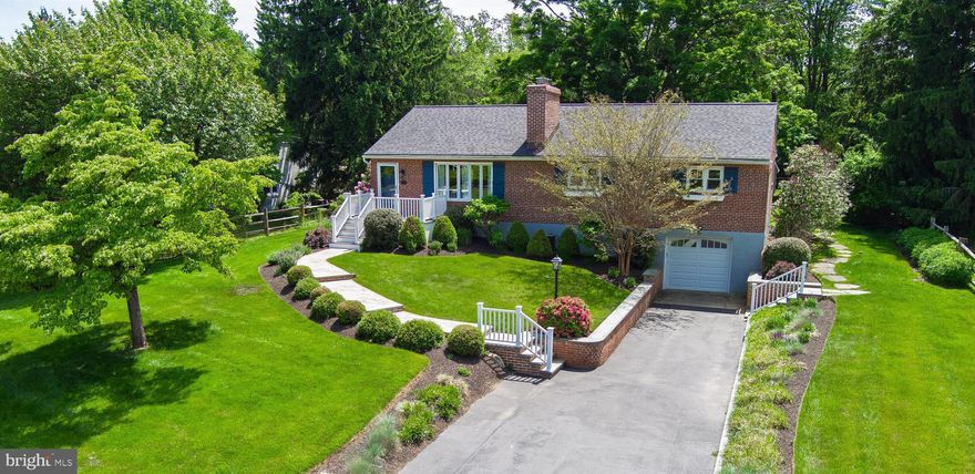 Impeccably maintained and updated home, situated on a gorgeous, professionally landscaped and fenced premium .69 acre lot with small barn, beckons its next lucky steward!  This charming brick home, with fully-finished lower level, includes every space to enjoy a gracious indoor / outdoor lifestyle, and is optimally located just ten minutes from Wayne and the R5 Regional Rail, and less than thirty minutes to Philadelphia International Airport!  Take the winding flagstone path to the front porch entry from which the sun-filled, open floor plan unfolds, with beautifully restored original hardwood flooring throughout.  The living room features one of two wood-burning fireplaces, flanked by custom built-in bookcases, along with windows wrapping two sides of the room that flood the space with beautiful natural light.  An archway connects the living room with the dedicated dining room, with another wall of windows showcasing views of the verdant backyard beyond.  The dining room is open to the updated kitchen, featuring man-made quartz counters, natural stone backsplash, plenty of storage, undercabinet lighting, updated appliances and egress to the rear yard and brick patio - the perfect spot to enjoy al-fresco dining under the canopy of a glorious 100+ year-old Sugar Maple.  Back inside,  find a full hall bath with enamel-over-cast iron tub/shower combo, and on-trend original green tile with black bullnose.  The updated main level primary en-suite features an oversized closet, along with barn-door entry into the primary bath, with walk-in shower and custom glass tilework.  Two additional bedrooms round out the main level, one with an extra large closet space......Take the stairway down to the expertly-designed, magnificently-executed finished lower level - an amazing space to gather with family and friends for movie night, thanks to the fully integrated projector, screen and surround sound system, professionally installed by Main Line Sound and Video.  This space features the second wood burning fireplace, custom built-ins to store all your games and books, a dedicated work space and a large welled window that welcomes the natural light.   The lower level can also be accessed via the attached one car garage with climate control and dedicated 220 sub panel.  The garage egress to the lower level  conveniently leads to a mudroom area with custom built-in bench, shelf cubbies and hooks to keep you organized, along with one of two entries to the well-positioned lower level powder room.  Laundry facilities with laundry sink are also just down the hallway.....Outside, find beautiful sunny and shady fenced yard areas,  stone pathways and plenty of gardening and play spaces!  The charming red barn has its own 220 electric, a rain barrel for watering the adjacent garden, and loads of possibilities as a playhouse, she-shed or storage for all your gardening and outdoor tools and toys!  This well-maintained property has been extensively updated and upgraded by the current owners and is conveniently located within close proximity to the area's best schools, shopping, two neighborhood parks and St. Albans Swim and Tennis Club!  Come see all this exceptional property has to offer!!!