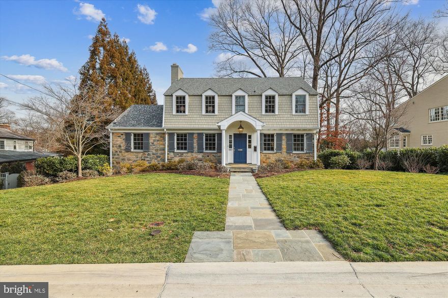 Welcome to 5017 Scarsdale Road, an exquisite residence in the sought-after Bethesda neighborhood of Sumner.  Nestled on a .25-acre lot, this center hall stone and shingle colonial features 5 bedroom, 4 full and 1 half bathrooms and over 5,000 livable square feet, with a three story addition added in 2008. The main level features a flagstone walk leading to a gracious foyer flanked on either side by a large living room with wood burning fireplace and a large dining room.  Past the living room is a paneled study with fireplace and large picture window looking into the private backyard. Hardwood flooring, crown and chair rail molding, new lighting and speakers throughout adorn the space. A large center island/table space kitchen with white wood cabinets and stainless steel appliances enhances the home and flows into a coffered ceiling family room with cherry cabinets, built in shelving and a stone fireplace. Exit the family room onto a screened porch and rear deck off the breakfast area, overlooking the landscaped and hardscaped private backyard. A convenient powder room off the hall completes the main level.
The second level consists of a hall bath, three bedrooms with ceiling fans, one which as an en suite bath and walk-in closet, linen closet and the fourth extensive primary suite bedroom including a cathedral ceiling, fan, built-ins, HVAC split system, primary bathroom with dual vanity sinks, heated floors, tub + shower and expansive walk-in closet.
The lower level houses a recreation room with built-ins, gas fireplace, a separate game room or study leading to a tree-lined flagstone patio, a large laundry room with cabinets and quartz counters, storage closets and a 5th bedroom and full bath. Two garages off a shared driveway complete the lower level space.  The Sumner neighborhood is ideally located off of the Massachusetts Ave. corridor and is part of the highly desired Woodacres/Pyle/Whitman cluster of schools providing easy access to shopping, public transportation, parks, the Capitol Crescent trail and more.