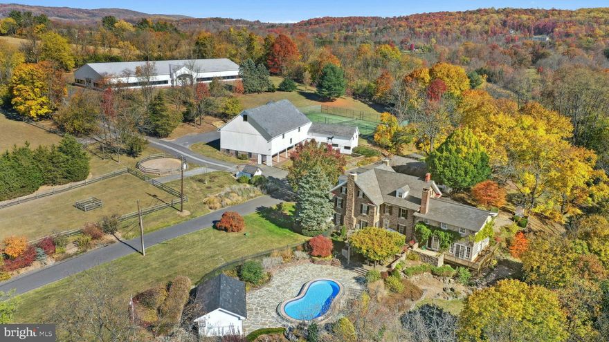 Situated amidst pastures, meadows, and hundreds of acres of preserved land, Molasses Creek Farm blends the renowned beauty of the Bucks County countryside with stunning modern enhancements. The expansive 58 acre property, set along a quiet rural road, is marked by the convergence of two pristine creeks.

Built by a Revolutionary War colonel in 1795, the stone farmhouse boasts original wood floors, deep window sills, period moldings and impressive ceiling heights. The formal entry hall opens to a spacious living room, with a marble fireplace and built-ins, as well as a family room with a wood stove and surround sound entertainment. Designed with entertaining in mind, the large dining room offers built-in storage and access to the butler’s pantry. The kitchen is a chef’s dream, with antiqued cabinetry, stainless appliances, granite and butcher block countertops, and a brick wood-burning fireplace as the focal point. The perfectly poised breakfast and sitting rooms extend this remarkable gathering space, offering superb views of the sparkling pool, wisteria covered pergola, outdoor entertaining kitchen, and terraced garden. 

Modern luxuries are found in bright and inviting bedrooms including a soothing primary bedroom suite with dual custom walk-in closets, laundry, full sauna and sun porch bathed in warm natural light. The en suite bath includes dual vanities, a claw foot tub, and spa shower. A second suite is on this floor, as well as two additional large bedrooms that share a hall bath. The finished third floor is an unexpected delight, with a wide sitting room, two large bedrooms, and a hall bath.The lower level includes a wine cellar along with a tasting room. 

State of the art equine facilities include the restored original bank barn from 1803. The tiled silo has been meticulously renovated to form the feed room. Five large stalls are fitted with metal kick plates and rubber mats, and the aisle and wash area is floored in stylish brick pavers.The heated tack room has ample space above with endless possibilities. There are five fenced pastures and a round pen. The 80’ x 200’ indoor riding arena built in 2010 has been designed to match the elegant style of the house and barn, with state of the art footing and screened windows on all sides to bring in the light and breezes.

Lovely gardens encircle the house, pool and outside kitchen with perennial beds featuring roses, echinacea, rudbeckia, hostas, lavender, clematis, geraniums and lilies which intermingle with hollies, yews and hydrangeas. In the rose garden stands a sundial that was custom made in England. The farmer’s milk house and carriage house with antique cobblestone courtyard stand proudly as reminders of days gone by. A synthetic turf tennis court is tucked into the hillside and a variety of plum, pear, apple and crabapple trees invite one to stroll through the orchard. The entire property is solarized with the panels discreetly hidden from view, another illustration of the harmonious blend of old and new at Molasses Creek Farm. 

For more than 200 years passersby have admired this graceful residence and picturesque farm located just 90 minutes from Manhattan and an hour from Philadelphia. The charming shops, innovative restaurants and cultural events of the Delaware River villages are a short drive from Molasses Creek Farm.