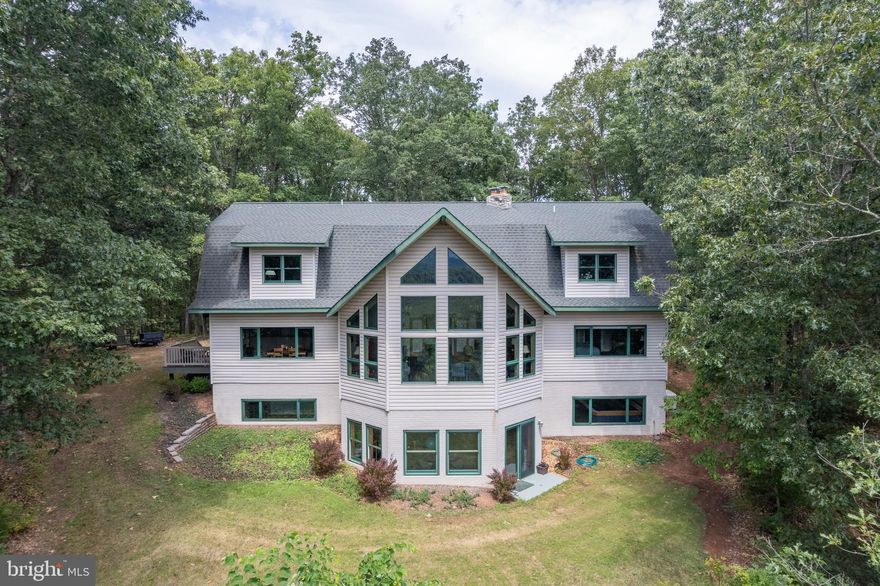 Remarkably peaceful Mountain Retreat on a quiet rural spur of Hampshire County West
Virginia’s most artsy little town, Capon Bridge. This exceptionally airy home offers
relaxed seclusion in abundance, yet also reliable 5G cellular internet. Built into the sunny
south-facing summit of 21.8 leafy forest acres, this 6,500+ square foot Retreat Home has
both sun-dappled woodland and over 1,700 feet of private frontage on the lively North
River. Designed for comfort with upsized rooms, high ceilings throughout, three spacious
private Bed/Bath Suites (one per floor, at alternating ends of the building) and 4 1⁄2 baths.
Second Floor also offers a 4

th large Bedroom or sizable Library / Office / Conference
Room, bonus loft & more. In photos see floorplans drawn to scale for each building level.
In addition to Three Suites & the possible Extra Bedroom, custom Luxury Amenities
include a generous two-person indoor sauna + indoor swim-in-place heated pool (7x13
countercurrent Endless Pool with performance upgrade). This much-appreciated pool is
well managed at comfortable lower chlorine levels with reliably fresh indoor air at all times
& everywhere in the entire 3-story building. This pool serves a very wide range of
personal health & fitness aims, from gentle still-water aerobics or rehab to all-out
Ironman-type endurance swim training. 16 kW Generator backs up all essential circuits
including pool room ventilation. Oversized detached 2-car garage (40 feet deep) plus
four more coordinating outdoor buildings. Though peace & privacy reign here 24/7/365,
this country delight is an easy drive to bustling Winchester, VA, with its full array of
stores, restaurants, and professional services - including the Valley Health flagship
Winchester Medical Center. One travels up the wooded driveway to reach the front door
of an intentionally modest-faced Rural Home. Yet on entering that doorway a truly
marvelous & uniquely uplifting delight quickly begins to unfold. From the welcoming
Foyer, through its large decorative glass French Doors straight ahead, one arrives in the
First Floor Great Room, featuring soaring wall & ceiling heights and a spectacularly tall
array of bright south-facing windows. One’s eyes are drawn inescapably to the stunning
over-the-treetops view of the never to be developed Ice Mountain Preserve and its
dramatic Raven Rocks. All who have ever entered this artfully constructed space have
personally expressed – sometimes with an audible gasp – the awe of its uniquely
inspiring & unforgettable mountain view. And this is the case at any season of the year
or time of day - due in part to the breathtaking outdoor color palette which transitions
faithfully all year long through several beautiful seasonal variations. To serve varying
needs of guests or owners, the Primary Retreat Bed/Bath Suite, with deep soaking tub in
custom-built deck, is also on this First Floor, creating an option for easy single-level
living. The entire First Floor was also designed as wheelchair-friendly, with many
carefully executed special features. Well-lit 48” wide interior stairways take one either up
or down to the other two living levels. Notably, the Walk-out Full Basement has brand
new Kitchenette & Hearth installations, and both the Sauna & Spa Rooms. Also, here
Bed/Bath Suite #3 can optionally serve as either Residential or Guest Quarters or
Complete In-Law or Live-in Assistant Accommodations, or a Highly Attractive Rentable
Space. Since the unique features of this fascinating Private Retreat are many, the Listing
Agent plans to be present at each showing to give info about all the Major Functions and
Systems of this amazing property, conduct tours to the long private River Frontage, and
show all Surveyor-Installed Boundary Line Markers. About 30 minutes to Winchester and 2 hours either way to Dulles Airport Or DC Beltway