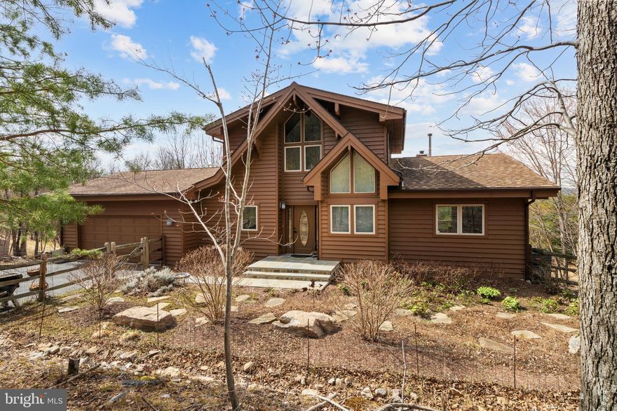 Breathtaking Mountain Retreat – A Rustic Gem!

This stunning cabin/lodge-style home offers 2,849 finished sq. ft. on 8.74 acres, blending rustic charm with modern comfort. Floor-to-ceiling windows showcase expansive mountain views, while vaulted wood-paneled ceilings, a striking stone fireplace, and an open floor plan create a warm, inviting space.
Inside, cherry and Brazilian hardwood floors flow through the living room, foyer, primary bedroom, and loft. The remodeled chef’s kitchen features stainless steel appliances, ample counter space, and a stylish tile backsplash. A cozy sitting room with a gas heater is perfect for morning coffee.
The primary suite offers wood floors, ample closet space, and serene views. The loft bedroom provides a flexible space for guests or a home office complete with an attached full Bathroom.
The fully finished basement adds even more versatility with luxury vinyl plank flooring, a spacious bedroom, full bath, rec room with a woodstove, wine room, and ample storage.

Recent Updates:
Water heater (2018) for efficiency
Water pressure tank (2013) for consistent flow
Repainted & sealed wood siding
Bluestone slate on front porch & walk

Outdoor Highlights:
Wraparound deck to soak in breathtaking views
Landscaped gardens plus space for a vegetable garden
Fruit trees (pear, peach, apple) for homegrown produce
Chicken coop conveys for fresh eggs daily

Convenient Location:
5 miles to I-81 (Martinsburg, WV & Winchester, VA)
30 miles to I-70 (Hagerstown, MD)
80 miles to Washington, D.C.

This mountain paradise won’t last long—schedule your private tour today!