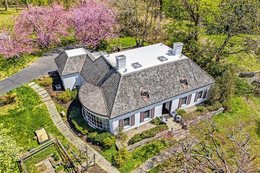 Set among the Gilded Era mansions of Elkins Park,  including the legendary Lynnewood Hall and the Elkins Estate, this custom-built French Provincial-inspired home is a rare and remarkable offering of extraordinary character, privacy, and beauty. 1735 Ashbourne Road set on 1.2 private, manicured acres at a coveted corner is a masterwork of character and architecture, thoughtfully updated for today’s lifestyle. With 5 bedrooms, 3 full and 2 half baths, and an estimated 4,340 sq ft of living space, this home offers an exceptional combination of original craftsmanship and modern upgrades.

A dramatic curved wall of floor-to-ceiling windows anchors the living room, flooding the space with natural light and framing breathtaking views of the private gardens is a true showstopper. Custom millwork throughout features built-in bookshelves, abundant storage, a two-sided fireplace, and a beautifully concealed bar behind the sitting room paneling. Original Saltillo tile floors with wood inlay in the entryway flow through the kitchen and sun porch, honoring the home's beginnings while complementing its renovations.

The chef's kitchen has been fully renovated with all-new appliances and cabinetry in an open-concept layout that opens to a four-season sun porch perfect for enjoying your morning coffee.  This sitting area, accented with a stone wall, is a seamless transition to the expansive rear patio. The formal dining room is framed by a stunning custom arched millwork entrance, with built-in cabinetry, a hidden butler's pantry, and rich random-width hardwood floors.

The first-floor primary suite features hardwood floors, custom built-ins, and a spa-inspired bath with custom glass cabinetry, hidden-outlet drawers, glass shower, soaking tub, and generous storage. A second main-level bedroom with abundant built-ins serves beautifully as a home office. 

The second floor offers three additional bedrooms, two renovated full baths, a generous loft, and a kitchenette — ideal for multigenerational living, au pair accommodations, or a private guest retreat.

Step outside to a gardener's paradise beginning with a bluestone patio with a natural gas grill and soothing waterfall feature.  The remainder of the grounds include a productive, fenced vegetable garden with raised beds and drip irrigation; a private orchard bearing peaches, apples, pears, persimmons, blueberries, blackberries, raspberries, strawberries, and figs; specimen cherry trees, azaleas, and perennial gardens in full seasonal color; an in-ground sprinkler system; and a flat rear lawn with room for a pool. Additional highlights include a ¾" cedar shake roof, all-new windows (except living room), new skylights, a two-car garage, garden shed, full basement with washer/dryer and half bath, and a laundry chute.

With only a short commute to Center City and close to many of the area’s universities and restaurants, a property like this, one with architectural distinction, thoughtful living, and extraordinary outdoor beauty, does not often come to market.