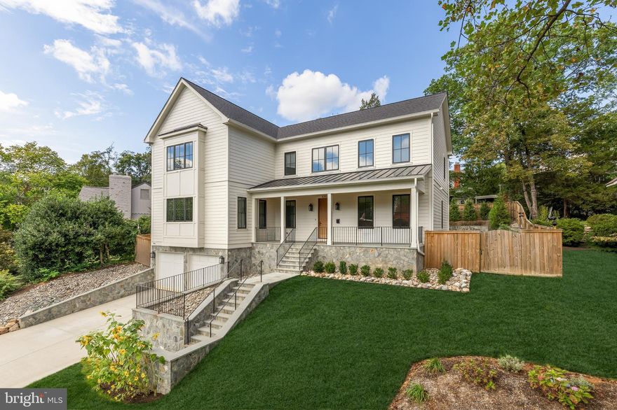 Tucked away on a quiet cul de sac in coveted Country Club Hills, 4283 38th Street North offers a rare blend of seclusion, sophistication, and striking design. Elevated above the street and framed by manicured landscaping, this custom residence was built in 2023 by CR Custom Homes and showcases where East Coast tradition meets West Coast style.

The exterior merges the charm of a modernized Colonial with warm farmhouse influences. Interiors, curated by Santa Monica designer Tracy Gilmore, embrace a refined Southern California aesthetic. A broad stone staircase framed by tiered retaining walls leads to a welcoming front porch, setting the stage for elegance inside.

A dramatic foyer, filled with natural light, spans the main level and highlights exceptional craftsmanship: wide plank white oak floors in herringbone, ten foot ceilings, eight foot quadruple hinged doors, Phillip Jeffries wallpaper, and motorized window treatments.

Off the entry, a private study balances a main level bedroom suite ideal for guests or multigenerational living. The formal dining room, introduced by a refined vestibule, features a large bay window and connects via a butler’s pantry to the kitchen.

At the center of the home, the kitchen is both showpiece and gathering space. Carrara marble wraps perimeter counters and backsplash, while a black leathered marble island adds contrast. Stacked inset cabinetry conceals appliances for a clean, modern look. An adjacent dining area and spacious family room flow seamlessly, with reclaimed wood beams, a linear fireplace, and arched built ins enhancing the atmosphere.

The primary suite occupies its own upper level wing. A vestibule introduces the serene bedroom, while a second leads to a boutique style dressing room with custom shelving. The spa inspired bath includes radiant heated floors, a walk in shower room, double vanity, and separate water closet.

At the top of the stairs, a loft creates a cozy reading nook and connects to three additional ensuite bedrooms with custom walk ins. A bold laundry room with patterned tile completes the level. The lower level includes a fifth bedroom suite, a large recreation room, and a mudroom accessing the two car garage.

The backyard is fully fenced and landscaped, with open lawn, hardscape, and mature greenery. A covered rear porch with retractable screens provides seamless indoor outdoor living for year round dining and relaxation.

Modern systems elevate efficiency and comfort, including impact rated windows and doors, backup generator, tankless water heater, integrated Sonos, comprehensive security, and extensive drainage infrastructure.

Located just a mile from Chain Bridge and moments from Glebe Road Park, the home offers easy access to city amenities and natural beauty alike.

4283 38th Street North is more than a home. It is a masterclass in design, comfort, and function. Every finish has been thoughtfully selected. This is luxury living at its finest.