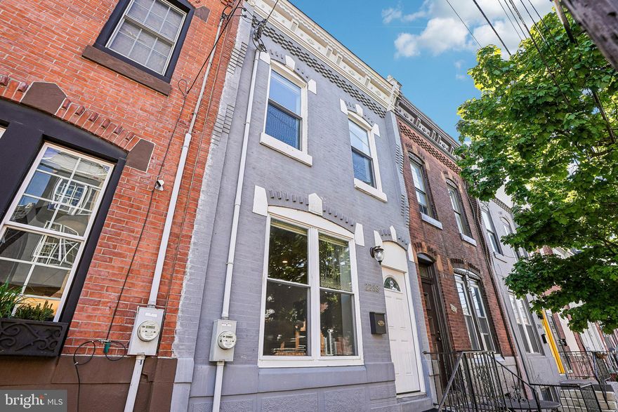 Located in the vibrant and ever-evolving Point Breeze neighborhood, this beautifully updated rowhome offers a refined blend of modern design and comfortable living. The open-concept main level is both bright and inviting, featuring rich hardwood flooring, soaring ceilings, and elegant chair rail detailing that enhances the living and dining areas. The sleek, contemporary kitchen is thoughtfully designed with stainless steel appliances, gleaming granite countertops, abundant inset cabinetry, a stylish tile backsplash, and a breakfast bar with seating—perfect for casual dining and entertaining. From here, exit out to a private, fenced-in expansive rear patio with a concrete surface, offering an ideal setting for outdoor gatherings, grilling, or quiet relaxation. Upstairs, the spacious primary suite continues the hardwood flooring and is accented by recessed lighting and a well-appointed ensuite bath featuring a walk-in shower. Two additional light-filled bedrooms and a full hall bath complete the upper level. The finished basement provides exceptional versatility with LVT flooring, recessed lighting, a convenient half bath, and a separate laundry and storage area—perfect for a media room, fitness space, or additional living area. Ideally situated near local shops, dining, a block from the Wharton Square Park and Playground, and easy access to transit options, such as I-76 and I-95, this home offers a dynamic urban lifestyle! Mortgage savings may be available for buyers of this listing.