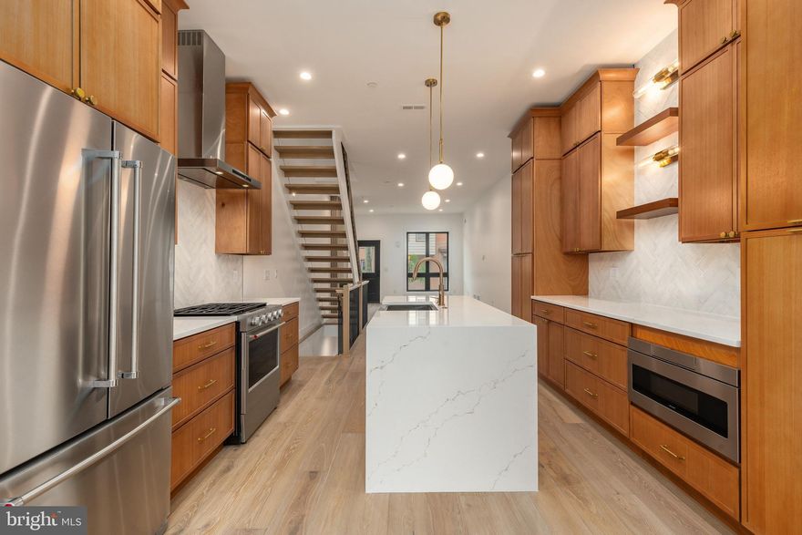 Stunning new construction in one of Philadelphia’s most desirable neighborhoods, offering the perfect blend of modern design, luxury finishes, and everyday convenience. This newly completed 4-bedroom, 3.5-bath residence showcases a bright, open-concept layout with 10-foot ceilings, wide-plank white oak flooring, and a striking architectural staircase that sets the tone from the moment you enter. The main living space is anchored by a sleek fireplace feature wall and flows seamlessly into a designer kitchen complete with floor-to-ceiling cabinetry, quartz waterfall island with seating, premium KitchenAid appliance package, and elegant finishes throughout. Thoughtfully designed for both entertaining and comfort, the home includes a convenient first-floor powder room and refined details such as champagne bronze fixtures and custom tilework.

The upper level offers a luxurious primary suite retreat featuring a wet bar with beverage center, spa-inspired bathroom with freestanding soaking tub, dual vanity, and oversized walk-in shower. Additional bedrooms are generously sized with modern design touches, while the fully finished lower level expands your living space with a second family room, bedroom, full bath, and abundant natural light. Enjoy multiple outdoor living areas including a private rear patio and an expansive rooftop deck with panoramic Center City skyline views. Located just minutes from top neighborhood destinations like Loco Pez, Cedar Point Kitchen, Reanimator Coffee, Suraya, Laser Wolf, and Pizzeria Beddia, along with nearby cafés, gyms, and parks such as Penn Treaty Park. Easy access to SEPTA, I-95, and major commuter routes ensures seamless connectivity across the city and beyond. A rare opportunity paired with a 10-year tax abatement—this is elevated city living at its finest.