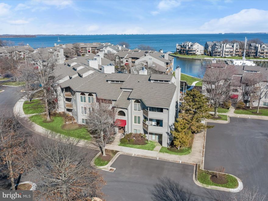 WOW! Nestled along the Chesapeake Bay,  this waterfront residence offers views of the community marina and the open water beyond. Situated in the sought-after gated community of The Village of Chesapeake Harbour, this beautifully updated two-bedroom, two-bath home combines modern elegance with coastal charm.
Step into the welcoming foyer, where an open-concept design unfolds with a soothing color palette freshly painted in 2022. Custom shades, including select electric-controlled options, add both privacy and convenience. The living and dining area boasts striking wood-look porcelain tile flooring, seamlessly blending gray and blue hues that echo the shimmering waters just beyond. Crown molding adds a refined touch, while the living room’s fireplace creates a cozy retreat. A three-panel sliding glass door leads to the expansive patio—larger than others in the community—where you can unwind in a private setting while soaking in the serene water views.
The well-appointed kitchen is both stylish and functional, featuring stainless steel appliances, including a recently replaced dishwasher, range, and microwave. An antiqued glass tile backsplash reflects natural light, creating a luminous atmosphere, while a pantry provides ample storage. Another triple-panel sliding glass door opens to a front patio, making this space feel bright and airy.
The primary bedroom is a tranquil haven, offering direct patio access through yet another sliding glass door, providing serene water views. The en-suite bath is a luxurious retreat with a double vanity topped with granite, a water closet, and a floor-to-ceiling tiled shower. A spacious walk-in closet with a built-in organizational system completes this private sanctuary.
Down the hall, the second bedroom is generously sized, accompanied by an updated full bath with a modern vanity. A sleek, stacked washer and dryer are tucked away in the laundry room, rounding out the home’s well-designed layout. Storage is plentiful, with custom-built closet systems enhancing organization throughout. For peace of mind, the brand-new HVAC system was upgraded in 2025, including an added air purifier.
Ample space is available for residents and guests in the unassigned parking lot.
The community offers resort-style living with premier water access and exceptional amenities. Enjoy dining at the on-site Beacon Waterfront Galley & Bar, take a dip in one of two pools with bay views, or relax on the private sandy beach. Outdoor enthusiasts will love the fishing piers, kayak launch, and scenic walking and biking trails. Tennis courts and a picnic area provide additional recreation options. Electric car charging stations offer convenience. Boaters will appreciate the Chesapeake Harbour Marina, featuring 81 wet slips with fresh water, electricity, and WiFi, as well as a full-service yacht facility.
Ideally situated near Historic Downtown Annapolis, Chesapeake Harbour provides a peaceful retreat while remaining within commuting distance of Baltimore and Washington, D.C. 
Experience coastal living at its finest—where the water meets effortless luxury. Property Updates: Porcelain tile flooring, dishwasher, range and microwave, washer & dryer, blinds, kitchen faucet and disposal, kitchen backsplash, interior paint, full bath vanity, closet built-ins, HVAC updates, and more!