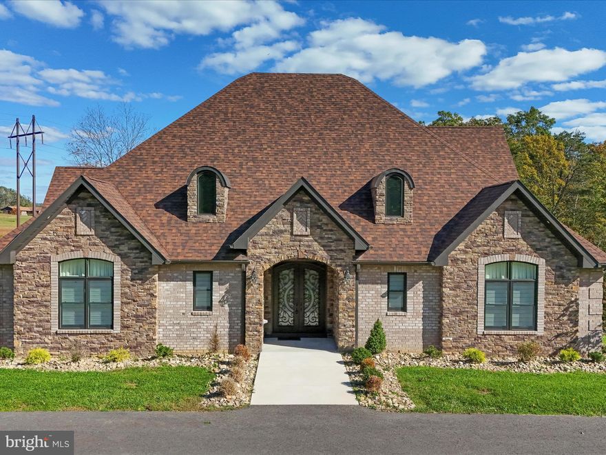 In a community where exceptional homes are the standard, this one still manages to stand apart. Perfectly positioned within the sought-after Lakewood Subdivision, this remarkable estate captures the essence of refined country living — blending architectural strength, modern comfort, and understated luxury on an estate-sized 2.13-acre lot. Thoughtfully designed and masterfully built, the 3,000± square-foot residence offers a lifestyle defined by craftsmanship, comfort, and quiet sophistication. The exterior makes an immediate impression with its full brick and stone construction, elegant arched dormers, and grand entry framed by professionally designed landscaping. A circular driveway welcomes guests with ease, while an in-ground sprinkler system and oversized three-car garage speak to both convenience and quality. Inside, the great room rises beneath vaulted ceilings with exposed beams, anchored by a dramatic stone fireplace that sets the tone for the home’s inviting, open layout. Sunlight floods the interior through expansive windows, illuminating hand-finished hardwood floors and accentuating the seamless connection between each living space. The gourmet kitchen is designed for both elegance and efficiency, featuring high-end cabinetry, double ovens, granite counters, a designer tile backsplash, and a generous center island that naturally draws people together. The main level offers three bedrooms and three-and-a-half baths, including a primary suite that delivers the feel of a boutique retreat — complete with a tray ceiling, walk-in closet, and a spa-style bathroom with dual vanities and a custom tile shower. A full unfinished basement provides endless potential for future expansion, recreation, or storage. Outdoors, a large covered rear deck and adjoining patio overlook manicured lawns and mountain views, creating an ideal setting for relaxing evenings or weekend gatherings. A whole-house backup generator and integrated lawn sprinkler system ensure year-round comfort and peace of mind. Every detail of this Lakewood home reflects pride, precision, and purpose — offering a rare opportunity to own one of Mineral County’s most distinguished properties. For those who value substance over show and excellence in every element, this residence is without equal.