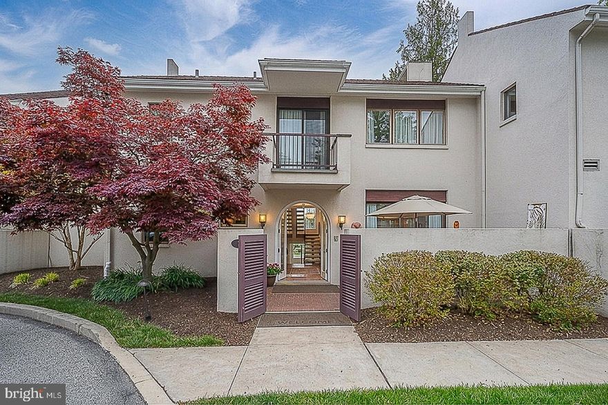 A rare offering in the sought-after Arbordeau community, one of the Main Line’s most architecturally distinctive enclaves, this beautifully reimagined two-story townhome sets a new standard for refined, turnkey living. Defined by its French village charm and serene, tree-lined setting, Arbordeau offers a lifestyle that feels both private and elevated.

From the moment you arrive, the architecture makes an impression. An enclosed front courtyard, private rear patio, and second-floor balconies provide multiple outdoor spaces designed for everything from morning coffee to evening entertaining, creating a seamless extension of the home’s living areas.

Step inside through a custom arched glass front door into a spacious, light-filled foyer, complete with a coat closet and powder room. The open-concept great room is the centerpiece of the home, anchored by a custom-built white Italian marble mantel and wood-burning fireplace. Floor-to-ceiling sliding glass doors open effortlessly to both the courtyard and Belgian brick patio, blurring the line between indoors and out and delivering the kind of indoor-outdoor lifestyle rarely found in townhome living. Ideally positioned within the community, the home enjoys a premium location with exceptional privacy and tranquil poolside views.

The dining area is designed with intention, featuring a built-in bar and custom accent wall, and flows naturally for both intimate dinners and larger gatherings. The gourmet kitchen has been fully reimagined beyond typical renovations, offering sleek, modern lines, updated appliances, a contemporary cooktop, and thoughtfully designed cabinetry that balances elevated style with everyday functionality.

Upstairs, a striking floating staircase leads to three spacious bedrooms, each finished with built-in custom closets for ample storage. The primary suite is a true sanctuary, intentionally designed to feel private, featuring a well-appointed walk-in closet and a fully renovated, spa-like en-suite bath with a walk-in steam shower, frameless glass enclosure, soaking tub, double vanity, and elegant stone and tile finishes. A discreet laundry closet with a stackable washer and dryer adds convenience without compromising design. Two additional bedrooms share a beautifully updated hall bath, continuing the home’s cohesive, modern aesthetic.

The lower level adds a layer of versatility rarely found, with direct access to two underground parking spaces, a spacious secondary entry, and a flexible bonus room ideal for a family room or gym, an additional office serving as another private retreat, or a dedicated workshop. Generous storage completes the space.

Living in Arbordeau offers a true lock-and-leave lifestyle. The HOA covers exterior maintenance—including stucco and roof repairs, gutter cleaning, snow removal, trash, water, and sewer—while an onsite manager and dedicated maintenance team ensure everything is effortlessly maintained. Set across 15 meticulously landscaped acres, residents enjoy resort-style amenities including a pool, clubhouse with entertaining space, and guest suites for visiting friends and family.

Ideally located just minutes from downtown Wayne, Devon Yards, and Jenkins Arboretum & Gardens, with easy access to major commuter routes and public transit, this home offers a rare balance of accessibility, privacy, and elevated design.

Opportunities like this in Arbordeau are limited—and rarely this complete.