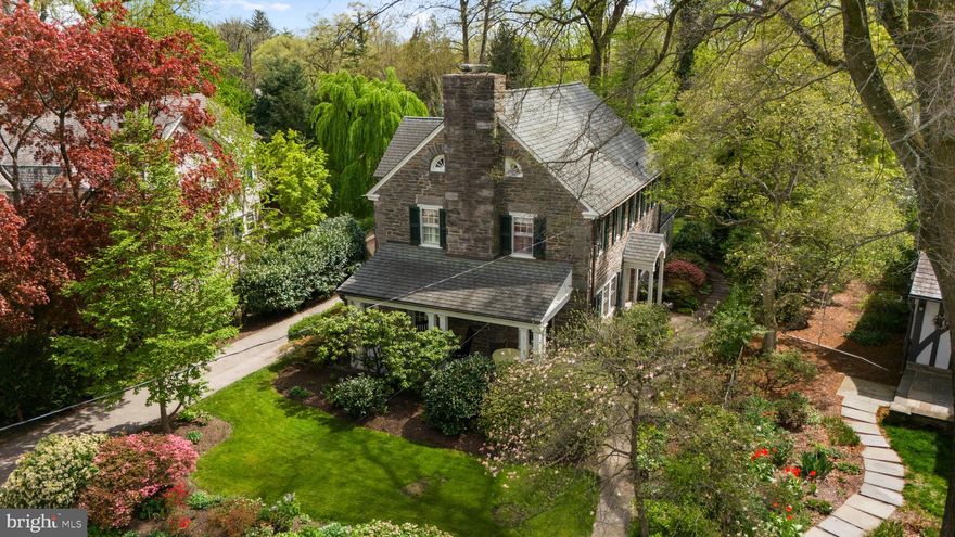 Tucked away on a quiet, tree-lined street in the heart of sought after Wyndmoor, Springfield Township, 7946 Pleasant Street is a beautifully maintained stone colonial offering four bedrooms, two and a half baths, and an oversized one-car garage. A charming slate walkway bordered by lush, flowering gardens leads to the arched front door and welcoming center hall, setting an elegant tone from the moment you arrive.
To the left, the sun-drenched living room welcomes you with a wood-burning fireplace flanked by  French doors that open to the front porch. Bay windows on either side of the room flood the space with natural light. The porch, overlooking lush gardens, offers a peaceful setting for al fresco dining or enjoying your morning coffee
Opposite the hall, the formal dining room captures the beauty of the side garden through another graceful bay window, offering a picturesque backdrop for gatherings large or small. The thoughtfully designed kitchen features granite countertops, stainless steel appliances, a pantry with pull-out shelving, and a versatile island workstation, all open to the adjoining living and dining spaces.
The family room addition, crowned by a vaulted ceiling and a full wall of sliding doors to the rear patio, creates a sunlit and airy space that’s perfect for everyday living or effortless entertaining. A powder room, hall closet, and access to the basement complete the main level.
Upstairs, the serene primary bedroom features ample closet space and a private entrance to one of two hall baths. Three additional bedrooms offer comfort and versatility, complemented by a second full hall bath. The third floor adds a spacious bonus area with abundant built-in storage, shelving, and a dedicated workspace, ideal for a home office.
Outside, enchanting garden paths wind around the home to the fenced rear yard, where a slate patio surrounded by mature trees invites relaxation amid birdsong and blooms.
Perfectly positioned just minutes from the charming shops and dining of both Wyndmoor and Chestnut Hill, and within easy walking distance to two train stations, 7946 Pleasant Street offers an exceptional lifestyle of comfort, beauty, and timeless appeal.