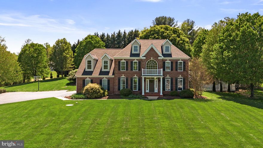 Set on an elevated 2-acre lot in Jenna Estates, this meticulously maintained brick front colonial offers more than 5000 finished square feet of pristine living space and a backyard centered around a heated in-ground pool and hot tub, with multiple patio spaces that feel like your own private resort. With up to 5 bedrooms, 4.5 baths, and a finished lower level with kitchenette, the dream home you’ve been waiting for is here. Inside, a two-story foyer with an oversized Palladian window opens to spacious living and dining rooms with crown molding, transoms, hardwood floors, and abundant natural light. The fully renovated custom kitchen (2019) anchors the main level with full-inlay alder cabinetry, 27 feet of granite counters, a 7-foot seamless island, gas cooktop, double wall ovens, and a breakfast bar with seating for up to eight. A butler’s pantry with sink, beverage cooler, built-in icemaker, and walk-in pantry adds function between the kitchen and dining room. The adjoining morning room is lined with windows overlooking the backyard, while the open, step-down family room features a floor-to-ceiling stacked stone gas fireplace. A private office, updated powder room, and mudroom with laundry complete the main level. Upstairs, the open landing leads to a spacious primary suite behind double doors that reveal cathedral ceilings, hardwood floors, a separate sitting room, dual walk-in closets, and a beautifully updated bath with soaking tub, walk-in shower, and dual vanities. A second bedroom includes its own ensuite bath and walk-in closet, while bedrooms three and four share a Jack and Jill bath with dual vanities. The finished lower level expands the living space with a cozy den, built-in bookcases, large recreation room, complete kitchenette with wraparound bar seating for up to ten, full bath, and a potential fifth bedroom - well suited for guests, an au-pair, or multi-generational living. Wide walkout stairs lead directly to the backyard, and a large storage and utility room adds function. Outdoors, the sparkling heated in-ground pool with diving well, waterfall feature, and attached hot tub is surrounded by multiple patio areas for dining, gathering, and relaxing. Stacked stone retaining walls, a pergola, mature landscaping, and a wide side lawn are fully enclosed with easy-care white vinyl fencing. The property is served by a strong 15 GPM well and includes a finished two-car garage with epoxy floors and storage area. Recent updates include a new roof (2025), HVAC (approx. 5 years), garage doors and opener (2023), and recent pool improvements including tile, concrete, and heater. Located with convenient access to Routes 99, 32, 70, 26, and 29, and close to Patapsco State Park, Liberty Reservoir, Turf Valley, and nearby hiking trails, this home combines pristinely kept space, a private setting, and thoughtful updates all in a central Marriottsville location. See more photos and video walkthrough at the virtual tour link.