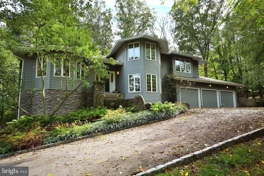If you've been dreaming of living in the woods but don’t want to give up the creature comforts of a spectacular custom built contemporary home, you won’t want to miss this once in a lifetime opportunity. Straddling Lafayette Hill and Chestnut Hill with an expansive backyard that backs up to the trails of the Wissahickon, this stunning residence is a true gem that seamlessly blends modern elegance with classic charm. Drive up the long driveway and park inside or outside of the 3-car garage. The moment you step onto the beautifully landscaped grounds, you’ll feel a sense of peace and tranquility. Sitting on 3/4 of an acre of wooded land, a myriad of patios and balconies offer incredible views from nearly every room in the home. With over 3,300 square feet on the main and upper levels and an additional approximately 1,100+ square feet of finished space on the walkout lower level, the inviting layout is perfect for both entertaining and for everyday living. Enter into a foyer that flows into the living room and dining room, all with dramatic cathedral ceilings. The living room has large windows that flood the space with natural light and a wood-burning fireplace. Down a short set of stairs, the dining room opens onto a deck to let in the breeze. Next, the gourmet eat-in kitchen boasts stainless steel appliances, granite countertops, and an expansive island and a small deck. The kitchen overlooks the lovely family room with wood burning  fireplace and stone floor to ceiling mantelpiece, the perfect set-up for cooking in the kitchen while the family hangs out together.  This room opens directly onto the patio and expansive backyard for easy entertaining and dining al fresco. The first floor also has a gorgeous office set far enough away from the main action of the home for quiet and privacy. A full bathroom and the laundry room complete this floor. As if this were not already more than you could ask for in the way of living space, the spacious finished walkout basement with brand new carpet comes complete with a huge family/media room/kids playroom with full daylight from sliders to the outside. This floor has a totally separate bedroom and full bath, making it an ideal in-law or au pair suite. It also has an additional space that can be used as a home gym or extra storage. The upper floor is home to a serene primary suite, complete with two walk-in closets and spa-like ensuite bathroom with rainfall shower, and a private deck overlooking the backyard and the Wissahickon. Three additional well-appointed bedrooms and a full bath complete this floor. The lush landscaping provides a tranquil setting, perfect for relaxation or play and exploration. Situated in a highly sought-after neighborhood, this home offers the best of both worlds: a peaceful residential woodsy environment with easy access to top-rated schools and vibrant shopping and dining options. Enjoy the perks of a suburban address including lower income taxes and highly rated public schools, while enjoying the best of Chestnut Hill and the Wissahickon and an easy commute into both the city and the suburbs. Don’t miss the opportunity to make this exceptional property your own! Schedule your private showing today and experience the unique perfect blend of luxury, comfort, and style in the most peaceful of settings.