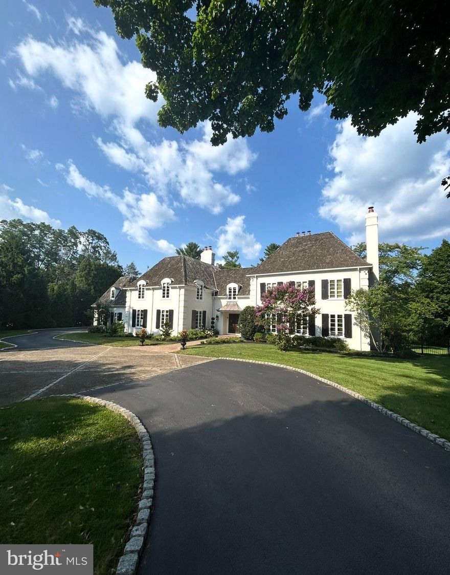 Set along the tree lined stretch of Parkes Run Lane in Villanova’s Radnor Township, this stunning French Colonial inspired home sits on more than an acre of level ground behind a private gated entrance. From the moment you step into the foyer, a dramatic front to back view draws your eye straight through to the pool and peaceful backyard, setting the tone for the home’s elegant design. The main level features beautifully proportioned living spaces including a welcoming living room, sophisticated den, and formal dining room. Custom doors, expansive rooms, and graceful archways throughout the home create a seamless sense of flow and style. The impressive gourmet kitchen serves as the centerpiece of the home, complete with a large island with seating, walk-in pantry, second sink, built-in desk area, and a bright breakfast room overlooking the pool and backyard. Entertaining is effortless, with the dining room connected to the kitchen through a fully equipped butler’s pantry offering an additional sink, oven, beverage refrigerator, and ice maker. The dining room also features an artist painted wine closet. Just off the kitchen is a spacious step down family room with abundant built-ins and plenty of room for gathering and relaxing. A generously sized mudroom with a sink and cubbies for eight or more helps keep daily life organized.The expansive lower level includes the inviting “Pub Room,” highlighted by classic Chicago brick flooring and direct access to the private backyard and pool area. This level also features a full bathroom, ample storage closets with one containing a washer and dryer. Upstairs, the luxurious primary suite provides a peaceful retreat with a sitting area, dressing area, an abundance of closets, and a spacious bath. Six additional generously sized bedrooms, each with their own en suite bathroom and walk in closet, offer comfortable accommodations. One bedroom is privately positioned, making it ideal for guests, an au pair, or an in-law suite. A basement area with high ceilings includes a basketball hoop with room for practicing foul shots while another space is for gathering, exercising  and storage. Designed for easy indoor outdoor living, the home also offers a beautiful covered outdoor entertaining area just off the living room, complete with a fireplace and flat screen television. Located within the highly regarded Radnor School District and close to many top private schools, this home offers a wonderful lifestyle. Residents can enjoy easy access to the Radnor Trail, as well as nearby downtown Wayne with its shops, restaurants, train station, and the beautiful gardens of Chanticleer. Major commuting routes provide convenient travel to Center City Philadelphia and beyond.This exceptional Villanova property combines comfort and thoughtful design for entertaining in one of the area’s most desirable settings.