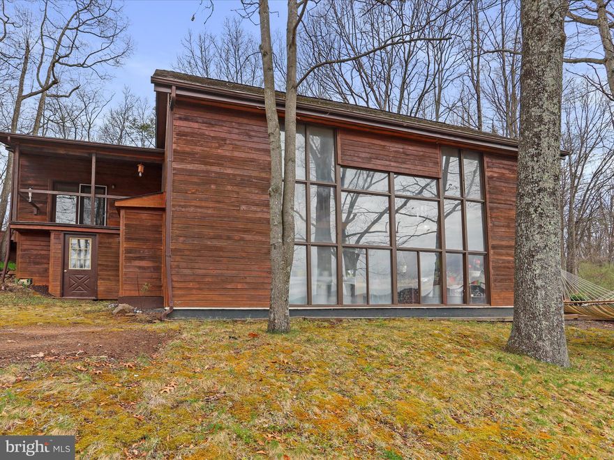 If you're searching for something ordinary, keep scrolling. But if you're after a mountain property that breaks the mold — something wild, peaceful, and built with purpose — welcome to your next chapter. This 20-acre escape in the rugged hills of Hampshire County, West Virginia, is as unique as the land it sits on. With a perfect mix of wide-open fields and towering hardwoods, this place offers more than just scenery — it offers potential. Watch the sun rise over the ridge from your front porch, hunt out back, or simply enjoy the kind of stillness that’s been lost in most corners of the world. There are no restrictions, no compromises, and no limits — just clean mountain air, total freedom, and easy access from a state-maintained road. And while it feels like you're a million miles away, you're fewer than two hours from Washington, D.C., giving you the best of both worlds. The centerpiece of this mountain compound is a handcrafted, solar-conscious contemporary residence — a one-of-a-kind home designed to be both beautiful and incredibly efficient. At 2,808 square feet, it features soaring ceilings, exposed beams, and custom millwork throughout. With five bedrooms and three full baths, there’s room for family, friends, and whatever else life throws your way. This home doesn’t just sit on the land — it belongs here. Built to harness the sun and withstand the seasons, it’s the perfect blend of comfort and sustainability. Step outside onto the expansive deck to take in the views, or head over to the detached storage building with a private office — ideal for gear, equipment, or remote work. As if that wasn’t enough, the property also includes a second residence — a 1,064 sq. ft. home featuring three bedrooms, two full baths, and a large detached carport. Whether you're thinking short-term rental income, guest lodging, in-law quarters, or extra space for a home-based business, this addition opens the door to countless possibilities. This isn’t just a place to live — it’s a place to build a life. A homestead, a retreat, a legacy. If you’ve been waiting for the kind of property that offers freedom, privacy, functionality, and purpose — you just found it.