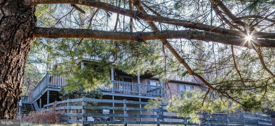 Don’t blink and miss this rare chance to own 1.24 acres bordering 3,000+ acres of parkland! Adjacent to the Appalachian Trail (merely a stone’s throw from the fenced front yard), this delightfully updated rambler is tucked in the woods for privacy yet located seconds from the national forest and community lake! MOUNTAIN VIEWS, VISTAS OF THE REMOUNT & SMITHSONIAN CONSERVATION/ZOO LAND & BREATHTAKING SUNSETS! This 2,400+ square foot treehouse-like home has four bedrooms, two baths and a potential for the seller to cover up to $10k in buyer’s closing costs!  FEATURES TO NOTE: Front covered porch with views (off great room), Side deck with views (off kitchen), Private rear patio (off dining area), Stone gas fireplace in great room (emits remarkable heat), Milled hardwood floors (in kitchen/dining/hall), Crown molding (in great room, dining area and kitchen), Ceiling fans in all bedrooms, Ceramic tile in both baths, Vessel sink, Kitchen bar area, Stainless appliances, Partially fenced yard (off lower recreation room) with area for covered storage, Recreation room (with wood burning stove)
BONUS CONVEYANCES: Electric car charging system, Smart home features (including a programmable smart thermostat, Ring system, security system with four exterior cameras w/audio and two keyless entry locks that can be controlled via phone), Nifty bottle/glass washer and Springs water system at kitchen sink, Rheem water softener and UV light, Front porch swing, Landscaping/flower beds ready to bloom (plus flowering trees including Redbud and Pink Kousa and pine trees for added privacy), Koi pond at base of front entry steps, Radon remediation station, Covered wood storage area in side yard, Framed large outbuilding in upper yard (built by prior owner in 2017/18 who had to suddenly move out of state and didn’t finish), Electric baseboards for back-up heat source (seller does not use).
UPDATES: New well cap 2021, Some fresh paint, Paved driveway w/ excess parking (over $8,500 spent in 2021), Upgraded doors (with built in blinds), Gas stove/oven 2021, Roof 10-15 years old,. Chimney repaired, See photos for 3 pages of updates by prior owners.  FYI: Owner works from home and enjoyed great high speed internet “Internet is cable with Xfinity (Comcast) I have the 1 gigabit plan very fast and reliable “ Electric car charging equipment is 50 AMP:  Home Flex Level 2 WiFi Enabled 240 Volt NEMA 14-50 Plug Electric Vehicle EV Charger