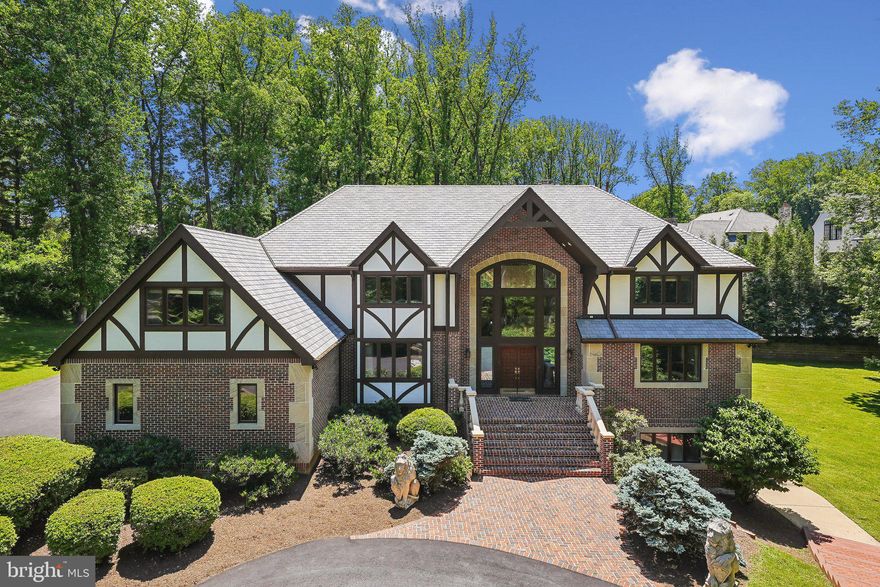 Just Reduced Unbelievable Value— Nestled between prestigious Langley Farms and Mackall Farms, this is without a doubt the perfect secluded location, with a long private driveway reminiscent of a quiet country lane. On a gorgeous parklike setting, this custom Tudor is surrounded by mature landscaping on 1.6 acres, providing a peaceful retreat and serene views from every window. Built to withstand the test of time with block, steel, and concrete, this stately home has a timeless style with approximately 9,000 square feet of interior space. Its welcoming entry is highlighted with accents of herringbone brick, cast concrete balusters, and limestone quoin corners. From the impressive foyer with soaring ceilings to the light-filled breakfast sunroom and granite terraces, this home offers space for grand entertaining or intimate gatherings.