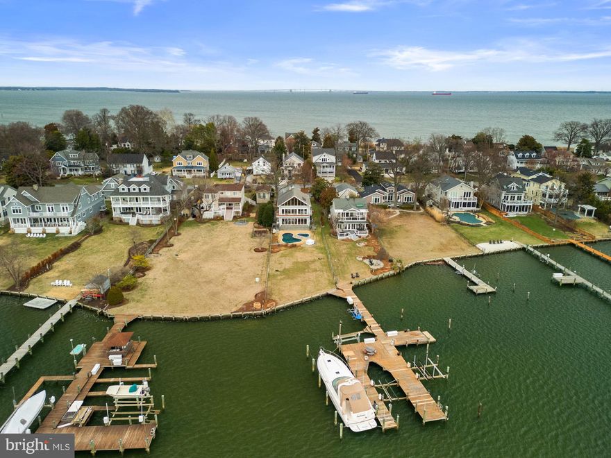 Welcome to 22 E Lake Drive! This exceptional waterfront residence offers striking architectural elements with expansive, light-filled interiors and seamless indoor-outdoor living along the Chesapeake Bay.
The main level open floor plan is designed for effortless flow and everyday living. The living room anchors the space, featuring a floor-to-ceiling stone fireplace and a wall of bi-fold glass doors that fully open to the pool and waterfront, creating a seamless extension of the home’s living and entertaining areas. Rich hardwood flooring, recessed lighting, and designer fixtures enhance the space throughout. A long, gallery-style entry hall offers a formal sense of arrival and includes a discreet powder room. The gourmet kitchen is both functional and elevated, featuring a large central island, custom cherry cabinetry, dark granite countertops, and a slate-tiled floor. High-end appliances include a gas range, double wall ovens, and a wine refrigerator. The slightly elevated, split-level design provides a clear vantage point over the dining and living areas while maintaining a defined culinary workspace.  
The home’s multi-level layout offers intentional separation of its four bedrooms for optimal privacy. The first upper level includes two well-sized bedrooms, a shared hall bath, and the expansive primary suite. 
The primary suite is a true sanctuary, defined by soaring wood-beam ceilings, a dramatic gabled roofline, and a wall of glass doors that open to a private balcony overlooking the water. A sliding barn door leads to the spa-inspired bath, wrapped in oversized charcoal slate tile and featuring an expansive wet room with multiple body jets and rainfall shower, a deep soaking tub positioned beneath a wall of windows, and a sleek floating dual vanity. The primary suite’s private balcony, finished with sleek cable railings, provides an elevated vantage point overlooking the pool, lawn, and panoramic water views. Above the suite, a unique loft space offers a quiet, sun-drenched retreat ideal for a home office, lounge, or library. Overlooking the bedroom below and framed by vaulted ceilings and a wide gable window, this elevated space captures sweeping waterfront views while maintaining a sense of privacy.  
A detached carriage-style garage includes a fully independent above-garage suite, offering exceptional versatility. This space features over 500 square feet of open living area with A-frame ceilings and large windows, a full bathroom, a modern kitchenette with quartz countertops and high-gloss cabinetry, and a dedicated laundry area. With its own private access, it is ideal for guests, an au pair suite, home office, or creative studio. 
The exterior is designed as a private waterfront retreat. A custom-shaped in-ground pool and elevated spa serve as the focal point of the backyard, surrounded by expansive decking for lounging and entertaining. A level, manicured lawn extends to the shoreline. 
Enjoy direct access to the Chesapeake Bay via a shared pier, perfect for boating, crabbing, or taking in the sunset. Unforgettable sunsets, a premier Bay Ridge Annapolis location, a short walk to the community beach, and quick access to Route 50 and Downtown—this is waterfront living at its finest. Schedule your private tour today!