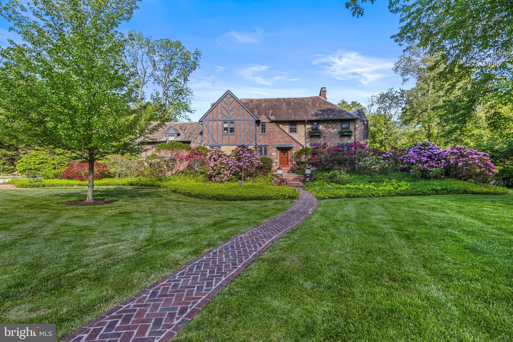 321 Airdale Road, Bryn Mawr | A storybook home-Classic Tudor Charm Meets Modern Sophistication in the Heart of the Main Line
Nestled on nearly an acre in a desirable North Bryn Mawr location, surrounded by some of the most charming streets on the Main Line, 321 Airdale Road is a beautifully updated brick and stone English Tudor. With its striking curb appeal, slate roof, and gabled architecture, this home effortlessly blends timeless character with refined modern updates— just a .5 mile walk to Ashbridge Park and minutes to the best of the Main Line.
The property welcomes you with a curved herringbone brick and bluestone walkway and professionally designed landscaping. Inside, almost 5000 square feet of living space features major renovations done in 2009, rich architectural detail, and spaces designed for both everyday comfort and elegant entertaining.
Enter the home through a beautiful wood paneled door into the entry foyer. A powder room accented by a leaded glass window is located just off the foyer. To the right, the den offers custom built-ins, a leaded glass window, and window seating. To the left, a beautiful, expansive kitchen features custom cabinetry offering abundant storage, an oversized center island with prep sink, granite countertops, two copper sinks, Viking 48” 6-burner range, and side-by-side paneled Sub-Zero refrigerator/freezers. A built-in desk and a sunlit breakfast area make this space as functional as it is beautiful. From the kitchen, access a convenient mudroom with built-ins that leads to the rear deck with mahogany railings — a spacious, private outdoor living space perfect for summer dining and entertaining. The mudroom also provides access to the 2 car attached garage and rear staircase.
The formal dining room features wide plank hardwood floors, a woodburning fireplace with custom panel surround, built-in glass-shelved cabinetry with lighting, and a charming stained glass window. The dining room overlooks an incredible step-down great room. This gorgeous room makes a big impact with its soaring ceilings, rich custom millwork, wide plank hardwood floors, oversized windows on three sides, window seats with built-in book shelves, a wood-burning fireplace with custom mantle and recessed lighting. Natural sunlight floods this space and French doors open to the beautiful backyard. Together, the dining and great rooms offer the perfect backdrop for everything from festive gatherings to quiet evenings at home.
The second floor is home to a luxurious primary suite—a serene retreat. The spacious bedroom is accented by sleek wood paneling that frames the windows, creating a warm, modern aesthetic. This sophisticated wood detail continues into the adjoining dressing room, where custom built-ins and dual fitted closets offer abundant storage. The spa-inspired en-suite bath features a soaking tub, dual vanities, and an impressive walk-through glass shower—your own personal sanctuary.
A 2nd bedroom includes its own en-suite bath, while 3 additional bedrooms share a hall bath. One bedroom is being used as a home office and another as a home gym. Off the 2nd floor hall, a laundry room with built-in linen closet adds convenience.
The finished walk out lower level offers versatility with a family room featuring a gas fireplace, wet bar, and exterior access. There's a second powder room, dedicated storage and utility rooms, and flexible space currently used as a workshop.
Additional highlights include: New heating system (2020), New central air (2022)
321 Airdale Rd. is in a prime walk-to location near Ashbridge Park that offers a playground and tennis courts, the Rosemont R5 train station just .7 miles away with service to Phila. and NYC. Convenient to Rosemont, Bryn Mawr, Villanova, Haverford shops and dining. Located in the top-rated Lower Merion School district (Harriton High, Black Rock Middle, Gladwyne Elem), and close to many private schools. Easy commute to many places via 476.