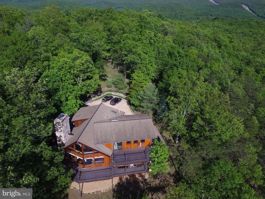 A festival of light, nature and masterful architecture set on a ridge above the Cacapon River. Total privacy on 42 acres.Features include 4 decks, back-up propane fuel,12.4Kw  solar array  (slashes bills),great lower level apt, sep BR over carport, 2 FP's,  fabulous materials thruout. Also big safe,shed,path along ridge with amazing views + eagles nest! 40 mi frm Winchester, 15 frm  Berkeley Spgs.