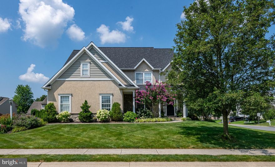 Welcome to 328 Cobblers Court,  a well-appointed residence on a corner lot in the Penn Crossing neighborhood of Lititz. A welcoming foyer introduces the home with high ceilings, abundant natural light, and a staircase accented by a pendant fixture. To the left, the dining room is framed by front-facing windows and detailed with beadboard wainscoting, crown molding, and a chandelier. The main living area features carpeting, large windows, recessed lighting, a ceiling fan, and a gas fireplace with tile surround and mantel. The home offers an open and connected layout, creating a natural flow between the living room and kitchen, with architectural columns and detailed window trim with crown molding adding character throughout. The kitchen has been updated with bright cabinetry and includes granite countertops, a center island with breakfast bar, pendant lighting, and a double sink with disposal. Stainless steel appliances include an LG gas range, Whirlpool dishwasher and refrigerator, and Maytag microwave, and a pantry provides additional storage. In addition to the formal dining room, the home features a separate dining area and a distinct breakfast area. The breakfast area is surrounded by windows, includes a ceiling fan, and provides access to the recently painted wood deck with metal railing, pergola, and steps leading to the backyard. A mudroom just off the kitchen includes tile flooring, a laundry area with washer and dryer, and access to the driveway and two car garage. The main level is completed by a half bath with tile flooring and wall sconces, along with a storage closet and access to the lower level. The finished lower level extends the living space with a family room and bonus room, both with carpeting and recessed lighting, as well as an office with tile flooring. A full bath includes tile flooring, wall sconces, ceiling lighting, and a stall shower. An additional unfinished area provides built in shelving, a workbench, concrete flooring, and flexible storage or workspace. The stairway to the basement features a chair rail with a ledge detail and wall sconces. The upper level features newer hardwood flooring throughout and a light filled landing with large windows, including a bay window that enhances the sense of space and natural light. Two bedrooms offer ceiling fans and double door closets, connected by a Jack and Jill style bath with dual sinks and a separate shower and tub area. An additional bedroom includes a ceiling fan and ample closet space. The primary suite is appointed with hardwood flooring, crown molding, large windows, a walk in closet with built ins, and a private bath with tile flooring, dual vanities, a soaking tub, and a stall shower. With its east to west orientation, the home benefits from natural light throughout the day. Exterior elements include vinyl siding and stucco with stone accents, an asphalt shingle roof, a paved driveway, and an attached two car garage. The property is situated within Manheim Township School District with convenient access to shopping, dining, major routes, and the Lancaster Airport. Schedule your private showing today!