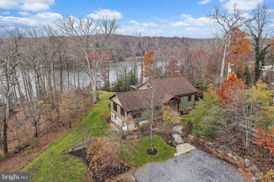 Arts & Crafts–inspired residence built in 2012 by Gate One Builders and designed by Fred Sieracki with exceptional materials and craftsmanship. Set on an elevated and private 5.46-acre wooded property, this home offers Broad Creek/ South River views, a deep-water, 100 ft private pier with boat lift, floating dock for kayaks, a living shoreline, and a fully fenced property with deer fencing. Exterior highlights include HardiePlank siding, custom stonework, curated landscaping, an outdoor shower, and a firepit.
Inside, the first floor is reminiscent of a lodge-style retreat with vaulted ceilings and blue knotty pine wood floors reclaimed from a 1900s South Carolina mill. The open floor plan features a masonry stone fireplace, a gourmet kitchen with marble countertops, and a spacious screened porch for entertaining with big vistas across the property. The en-suite primary spa bath includes porcelain tile floors and marble countertops. Two primary suites plus a third bedroom/office are located on the main level.
The walkout lower level provides flexible living space with a potential bedroom/sitting room, full bath, concrete flooring, and abundant storage. Enjoy spectacular sunsets, a gravel driveway with ample parking, and the feeling of being worlds away—yet just minutes from Whole Foods, Starbucks, and everyday conveniences. Seller prefers a 60 day close and all prefers to sell 95% of all furniture.