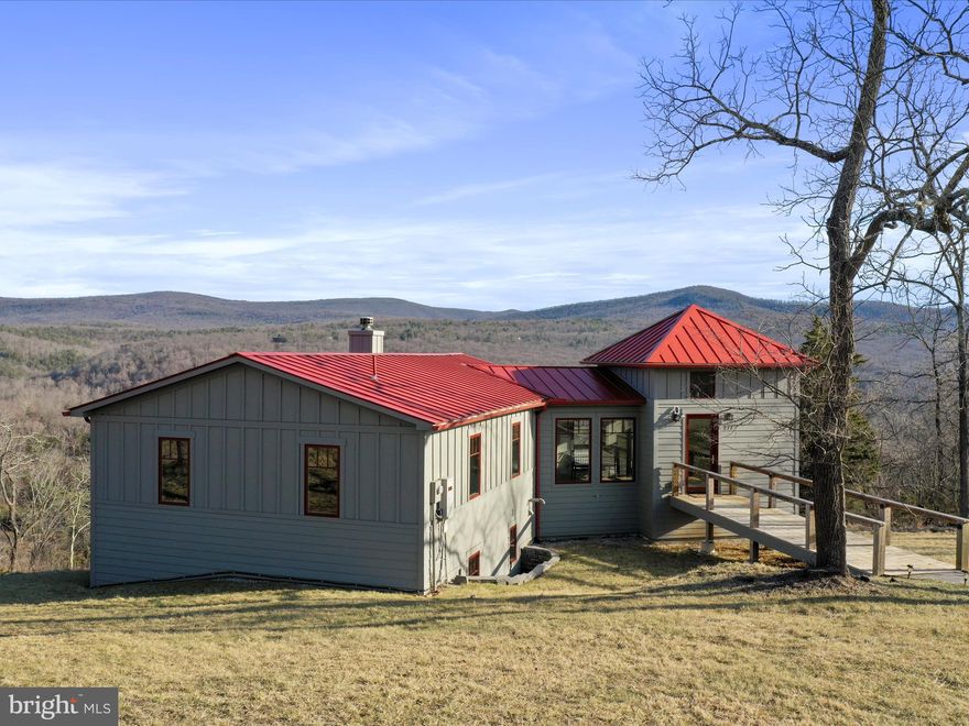 A Modern Mountain Retreat with Stunning Views! Perched high above the beauty of the Lost River Valley, this home features 3 bedrooms and 3.5 bathrooms, positioned to embrace panoramic mountain views of the George Washington National Forest from nearly every corner of the home inside and out. Step inside to a light-filled entry foyer, where walls of windows frame the awe-inspiring mountain landscape, flooding the space with natural light. The open-concept living, dining, and kitchen area is designed for effortless flow, featuring wide-plank wood floors that enhance the home’s modern-rustic aesthetic. The living room is anchored by a wood-burning fireplace, offering a cozy focal point perfect for gathering with family and friends, all while enjoying the ever-changing views. The gourmet kitchen is well-appointed with stainless steel appliances, a 5-burner gas range, a built-in microwave over the stove, a dishwasher, and a wine captain. A half bath is conveniently located nearby for guest comfort.  Located on the entry level, the primary suite is a private sanctuary, offering a walk-in closet, a full bathroom with double vanity, a walk-in tiled shower, and a Toto Washlet toilet. Large windows bring the outdoors in, ensuring that even from bed, you wake up to breathtaking scenery. The lower level expands the home’s living space, featuring a foyer/mudroom, a comfortable secondary living area with a gas Jøtul stove, and two additional bedrooms. Each bedroom includes its own en-suite full bathroom with a walk-in tiled shower, providing privacy and comfort for guests.
Designed for year-round enjoyment, the home features a large screened-in porch with exposed beams and a large sunny deck, ideal for entertaining. For the ultimate relaxation, a Nordic Spa hot tub sits on a private concrete patio, offering total seclusion and uninterrupted panoramic mountain views.  The property is sited on 5.01 acres, equipped with a private well, 20 kW Generac generator, and a buried propane tank, ensuring energy efficiency and peace of mind. The standing seam metal roof enhances both durability and architectural appeal, while cable railings add to the home’s contemporary charm. Adding to its appeal, the home is offered furnished, making it a completely turnkey opportunity for those looking for a seamless transition into mountain living. Located within the highly desirable Lost River Valley Property Owners Association, this home offers fiber optic internet, underground utilities, and well-maintained private roads for seamless connectivity and convenience. Situated near Lost River State Park, Trout Pond Recreation Area, and an array of outdoor adventures, with easy access to local markets, restaurants, and boutique shops. Less than two miles away, the Guesthouse Lost River, an award-winning inn, offers fine dining, a bar, lounge, and regular entertainment, further enhancing the experience of mountain living. This home presents an exceptional opportunity for those seeking an unparalleled lifestyle in the heart of Lost River Valley. Visit the Interactive Virtual Tour & Video-Walkthrough links to explore this incredible home!