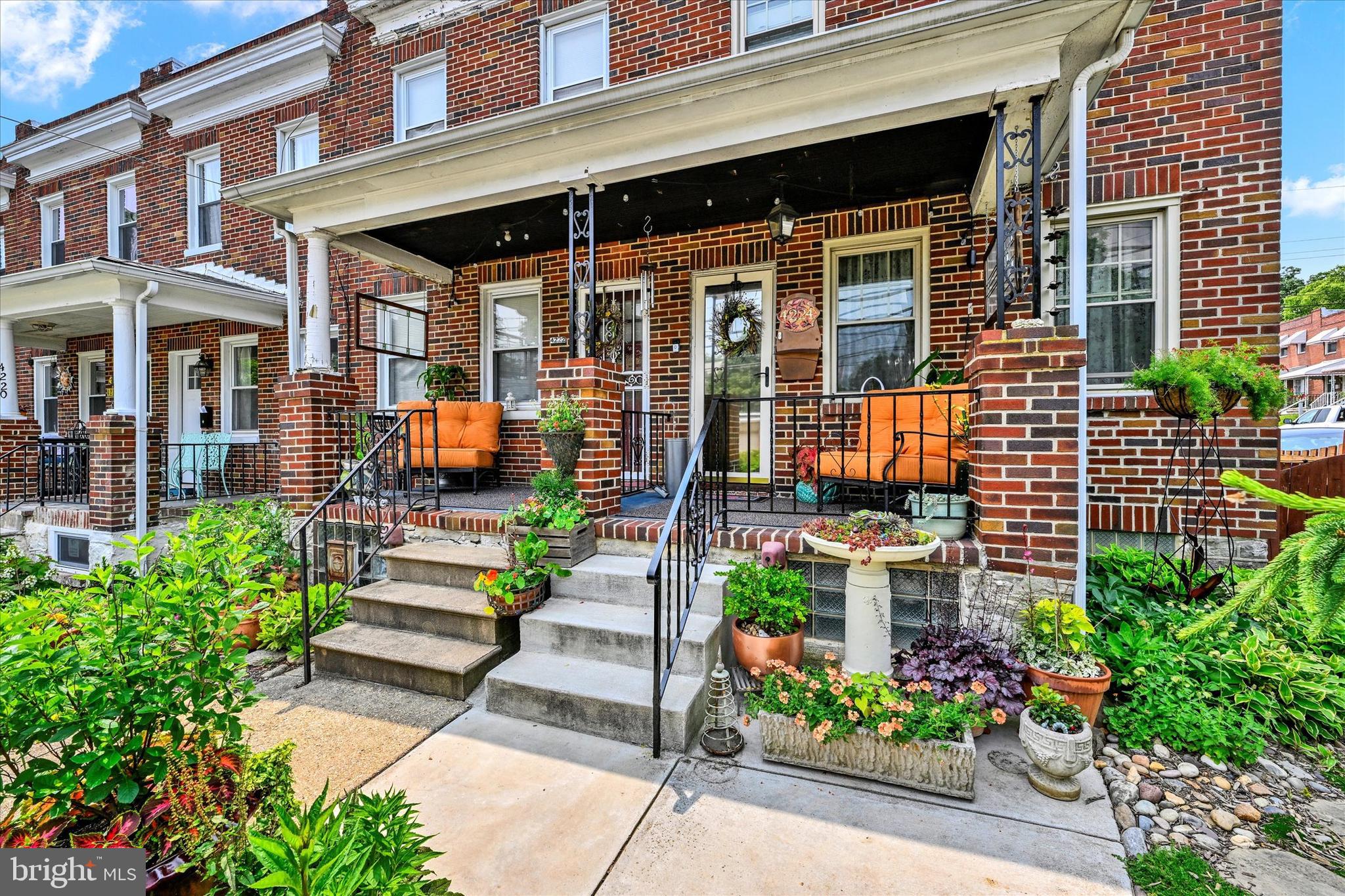 Tucked away like a secret garden, this charming end-unit all-brick home is surrounded by lush greenery that offers privacy and tranquility from the moment you arrive. A quaint front porch welcomes you into a light-filled interior featuring true hardwood floors throughout the living and dining areas. The beautifully updated kitchen is a standout with stainless steel appliances, a gas range, granite countertops, handcrafted cabinetry, and a whimsical mural that adds artistic flair. Upstairs, more hardwood floors lead to a spacious primary bedroom with double French closets and a calming earth-toned palette throughout. The bathroom feels like a retreat, with thoughtfully designed cabinetry, built-ins, and distinctive tile work. An additional bedroom with a cozy office nook completes the upper level. The lower level offers a versatile family room and half bath—perfect for entertaining—along with a built-in reading nook, extra storage, and a laundry area with wet bar. Step outside to a fully fenced backyard oasis, featuring mature trees, tiered decking, and lush landscaping—a true paradise for garden lovers.