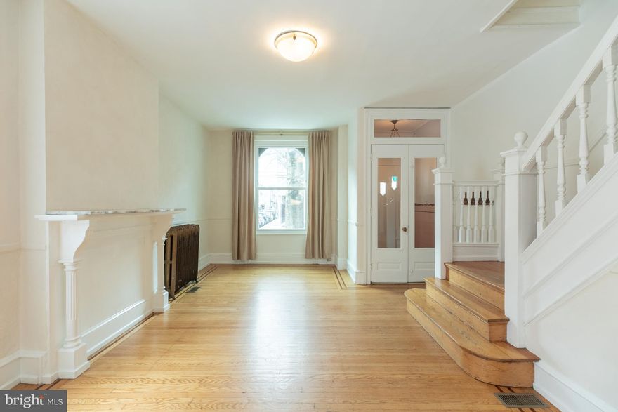 Here is a great opportunity to own a wonderful historic corner property in the lovely South Philadelphia neighborhood of Melrose. The fine brick facade, brownstone arches, and an elaborate cornice wrapping around to the Carlisle Street side beautifully conceal a home that has been updated for modern living while retaining many historic elements both inside and out. Step through the wide front door into an original foyer with tiled walls and floors, illuminated by an antique pendant lamp at night, and double full light doors by day. The foyer opens to a large living area with high ceilings flanked on one side by a painted wood mantle and on the other side by the original staircase. A large south-facing and an east-facing window provide ample natural living room light. Oak flooring with a walnut border extends from the living room through the wide archway into the dining room and right up to the open kitchen at the rear of the house. Beautiful original radiators provide warming radiant heat while a separate AC System provides cool air in the summer months. The dining area is very spacious. Below two east-facing windows is a wall-length window seat with storage cabinets.  There is plenty of room for dinner parties for friends and family. A contemporary kitchen with warm walnut-stained cabinets and white Corian countertops wraps around all four sides, including a peninsula with a counter to pull up a couple of stools. There are modern stainless steel appliances. Two windows help keep the natural light flowing through this entire living level. Beyond the kitchen is a private patio ready for your personal touches to create an urban oasis. Upstairs, you will find original pine floors running throughout the floor, three spacious bedrooms, and a hall bath. The primary bedroom at the front of the house has an ensuite full bath plus 12' of closet space. Again, being a corner property, all the rooms are light-filled through the large windows. The basement is large and dry, so great for storage. It is also home to the washer and dryer, as well as a double porcelain utility sink. If you don't know this neighborhood yet, there is so much to explore. It is a short walk from great decades-old purveyors such as Cascia's, Dad's Stuffing, L'Angolo, and Ritner Hardware, as well as being a short walk to the South Philly Food Coop, Cafe Nhan, Ultimo, several good Mexican spots, and the Broad Street Line. This is a gem of a neighborhood and a property that you don't want to miss.