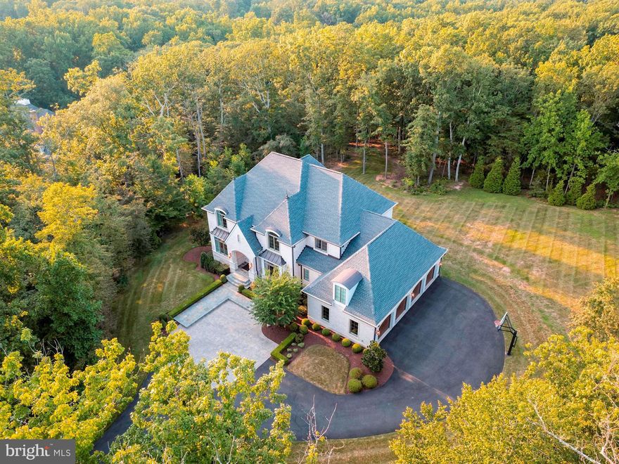 Welcome to this extraordinary, custom-built estate home perfectly nestled on over three treed acres for an abundance of privacy - while also being only minutes away to all of your present-day amenities. This one-of-a-kind property is a home unlike any other... Around each and every turn you will find that the most thoughtful details have been meticulously picked out to create a home that exudes a balanced combination of refined elegance and modern charm. This stunning all brick home boasts incredible design features including a four-car side-load garage; gorgeous hardwood flooring throughout the majority of the home; soaring two story Foyer entry with intricate tile flooring; detailed ceiling moldings in the elegant Dining Room; private Home Office with handsome built-in cabinetry; a spectacular main-level In-Law Suite that can serve as a secondary Primary Bedroom; Family Room with a cozy gas fireplace seamlessly flows to extend your living space to the outdoors with access to the covered terrace and outdoor firepit (and space for a future pool!); gourmet Kitchen perfectly suited for Chefs of every level featuring Wolf and Subzero professional grade appliances, a beverage fridge, an induction cooktop, a steam-oven, a center island, quartz counters, and a dream walk-in pantry; optional second Laundry Room on the main level; French doors will lead you into the luxurious Primary Suite on the upper level hosting its own Sitting Room and lavish En-Suite where you will find dual vanities, a stand alone soaking tub, a spa-shower, his and her walk-in closets, and a dressing area; two additional Bedrooms are also located on the upper level, each with their own private Bathroom; upper level Laundry and Sorting Room with beverage fridge; walk-in attic space on this upper level fully insulated and temperature controlled; a fully finished lower level with 9.5' ceilings is the perfect space to entertain family and friends with a Game Room, Media Room, full wet-bar with dishwasher and beverage fridge, a Guest Suite with Sitting Room and private entry/exit to the outdoors, a full Bath, a Home Gym, and an abundance of storage space in the unfinished utility room. Additional outstanding features include a three-zone HVAC system (one for each level) with air quality filtration system, indoor sprinkler system, water filtration system, generator, electric car charging station, extensive outdoor lighting,  Located just a short drive to downtown Leesburg, Loudoun County Wine and Hunt Country, shopping at the Leesburg Outlets/One Loudoun/Brambleton Town Center, access to commuter routes (Dulles Green Way, Dulles Toll Road, Routes 50/7/28) and minutes to Dulles Airport, and so much more. This phenomenal property is waiting to welcome you home!