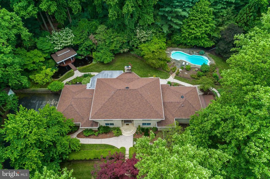 **DON'T FORGET TO TAKE THE 3D VIRTUAL TOUR!  https://my.matterport.com/show/?m=yuWtqLNeewC&brand=0  **  Turn down the tree-lined driveway that leads to this enchanting, private property nestled within beautifully manicured grounds of flowering specimen trees and colorful perennials. The Grand Foyer dramatically greets visitors with a sweeping split staircase and offers access to graciously-proportioned living spaces - all with impressive views of the grounds from abundant windows and glass doors.  The Main Level Master Suite is unparalleled! New luxury plank flooring and a gas fireplace in the MBR, one marble MBath w/ stall shower & spa tub , separate Boudoir, 2nd Toilette w/ soaking tub, commode & bidet & marble vanity plus a STUNNING custom Dressing Room w island! The Kitchen is the envy of any chef featuring double Dacor gas ranges w/ vent hood,  exceptional counter and custom cabinet space,  a center island w/ breakfast bar and more! Enjoy morning coffee or afternoon tea in the Sunroom w/ gas fireplace while overlooking the rear yard and listening to the relaxing  sounds of the 2 waterfall features.  Enjoy the chirping of the birds while lounging on the pagoda or taking a dip in the pool.  An impressive place to call home!