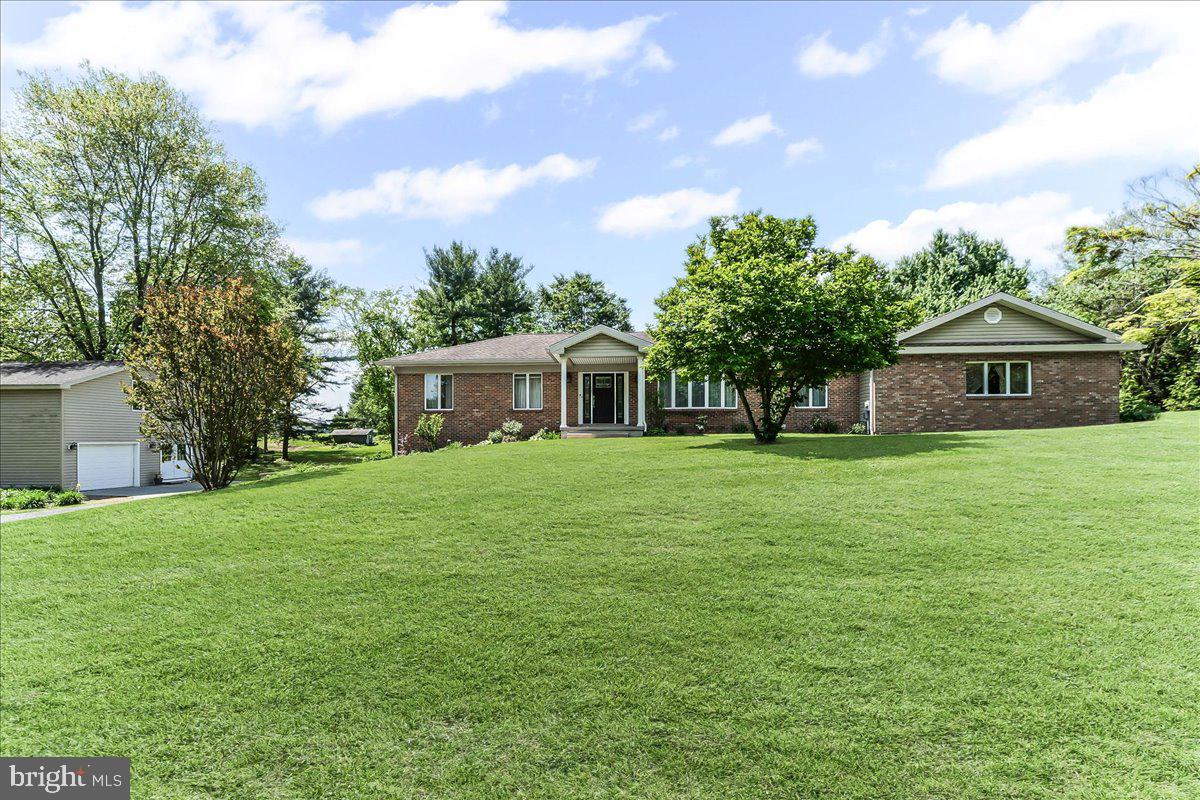 Imagine a brick rancher on an acre lot with 5 bedrooms, 3 ½ baths, an attached garage and a finished basement. Add a lovely first floor in law suite and finish it with a detached garage, complete with workshop and second floor loft, for all your hobbies and projects, and your search is complete! The main house is open and airy with updated flooring and a living room to dining area combination that opens to a lovely, updated kitchen that comes complete with a large island, farm sink, stainless appliances and lots of white cabinets that are topped with gleaming quartz. Family room opens off the kitchen in the popular floor plan of 2025! Large opening, from the family room- kitchen area draws everyone to the sunroom, complete with a ceramic tile floor, ceiling fan and sliders to the patio—a perfect spot for those evening meals or morning cups of coffee. Primary bedroom suite features gleaming cherry floors, a walk-in closet with organizers and an updated bath. The additional 2 bedrooms, with ceiling fans, are easily serviced by the hall bath and one bedroom has built in beds with dressers! Finished basement features a fourth bedroom, with an outside entrance, rec room, laundry room and a powder room with an unfinished shower. The 2008 addition of the in-law area could also be used as additional living area for the main house. Eat in kitchen, with custom cabinetry, laundry room with a large hidden storage area, living room, office area, bedroom, sunroom and bath combine to create an amazing bright and airy space. Finally, to complete the picture is the detached garage area, with room for a workshop, storage for your lawn equipment and a walk up second floor that is perfect for your hobbies or a getaway area (it was designed to house an amazing model railroad display). All of this on a 1-acre lot with lovely plantings and a level back yard for all your outdoor activities as well as easy access to 896 for commuting north and south.