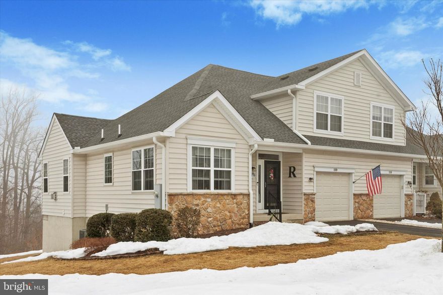 Welcome to 129 Haslan Lane in the sought-after Villages at Hillview, a premier 55+ community in Coatesville. This beautifully updated carriage home has been thoughtfully refreshed with neutral paint throughout, hardwood flooring  and upgraded LED lighting and convenient "Christmas Package" are just a few of the many convenience features of the home. All major components have been recently replaced for peace of mind - newer Roof (2020), new HVAC and new water heater. The spacious great room is highlighted by a cozy gas fireplace with granite hearth, while the sunroom offers abundant natural light and new sliding doors to a private deck with scenic views—perfect for morning coffee or evening relaxation. The main-level primary suite includes a full bath, double vanity and walk-in closet while the upper level provides an additional bedroom and full bath, ideal for guests, along with extra storage closets. A secondary office space completes the second floor. A full walk-out basement, already plumbed for a full bath, offers endless potential for future finished living space.  Enjoy the maintenance free composite deck in the upcoming summer months or unwind on the paver patio backing up to the woods. Low-maintenance living and resort-style amenities including pools, clubhouse, fitness center, tennis courts, walking paths, and a full calendar of community activities.