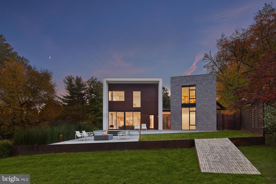 Nestled amidst the verdant bends and winding hills of Chevy Chase, 9119 Levelle Drive is a
textbook showcase of cutting edge modernism.  Designed in 2021 by the acclaimed Robert M.
Gurney, FAIA and built by Ted Peterson of Peterson and Collins Builders as his personal
residence, the extraordinary skill and craftsmanship is evident throughout and unparalleled.
This singular home is yet another award-winning example of geometry, brilliant manipulation of
light, artistic use of glass, and conformation with its natural surroundings. Prominently sited on a
coveted lot of just under an acre, towards the end of a no-through road, the approaching
driveway opens into a rectangular motor court. Two likewise rectangular volumes are situated in
a narrow ‘V’ configuration, connected by a glass bridge housing the front door. A transverse
gallery introduces the fully open concept main level by its informal spaces first. The chef’s
kitchen anchors said space, blending design and function with floor-to-ceiling minimalist, light
wood cabinetry concealing a comprehensive suite of commercial-grade appliances. An
extraordinary oversized center island, clad in light stone slabs with integrated seating and
waterfall edges, spans the entire length of the room. A flooring change from wood to tile, both
outfitted with radiant heat, signifies the transition into the adjacent light-filled breakfast area. A
generously proportioned, continuous living and dining area comprises the majority of the main
level. The latter is backed by full-height panes of glass, letting in tranquil wooded views. The
former, anchored by an abstract half-wood half-mosaic fireplace wall, interacts with said views
via a wall of glass which can be opened to blur the relationship between indoor and outdoor
living. The central staircase, artfully crafted from wood and glass, is both a showstopper and a
structural feat, which connects all levels of the home. The upper level contains private quarters,
including a stunning primary suite resting amidst the treetops. It features generous closet space
with custom built-ins, and the ubiquitous spa-inspired bath with a soothing ambiance attributed
to neutral woods and large panes of glass, as well as all the usual accoutrements. Secondary
bedrooms are well-proportioned, luxuriously finished, and arranged so as to maximize privacy.
Across the glass bridge is the second volume, clad in dark ground face block to contrast the
main volume’s white stucco. On the ground level, it houses an oversized garage with a frosted
glass door as well as a cozy living space. Upstairs is a fully self-sufficient apartment. The
kitchen mirrors that of the main residence, with full-size SubZero and Viking appliances, and a
peninsula island overlooking wooded views beyond the adjacent living area. A private bedroom
featuring a large walk-in closet, as well as a luxurious fully-tiled bath complete the unit.
Enclosed by full fencing constructed of mahogany and steel, the rear lawn comprises terraced
outdoor living spaces designed to engage with the lot’s topography. They include dual-level
patios with a fire pit, ideal for al fresco entertaining, dining, or lounging on a crisp autumn
evening. Further beyond, private rolling hills are surrounded by total privacy. Convenient to the
shopping, dining, and entertainment of both downtown Bethesda and Chevy Chase, as well as
the Nature Conservatory and trails along Beach Drive and major commuter routes, the location
is enviable. Not to be replicated in its architectural significance, 9119 Levelle Drive is a true one-
of-a-kind offering.