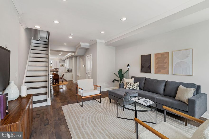 Welcome home to this spacious and versatile 2-bedroom + den, 3.5-bathroom home with a finished basement and an oversized rear yard—perfect for indoor-outdoor living in the heart of Point Breeze. Situated on an extra-deep 72-foot lot, this property offers a rare amount of outdoor space in the city. The main level offers an open-concept living and dining area featuring tall ceilings, rich wood floors, crown molding, recessed lighting, and a convenient powder room. The kitchen is bright and modern, equipped with white cabinetry, granite countertops, a glass tile backsplash, stainless steel appliances, and direct access to the large backyard—ideal for entertaining or relaxing outdoors. Upstairs, the sunny primary suite spans the front of the home with a walk-in closet and an en-suite bathroom complete with a dual marble vanity and tiled tub. A second bedroom, full hallway bathroom with stall shower, and linen storage complete this level. The fully finished lower level adds incredible flexibility with a spacious den or home office, a third full bathroom, a laundry closet, and a bonus room that can function as a third bedroom or guest suite. Enjoy Center City views from your doorstep and the best of city living with close proximity to local restaurants, parks, public transportation, and more. 2 years remaining on the tax abatement!