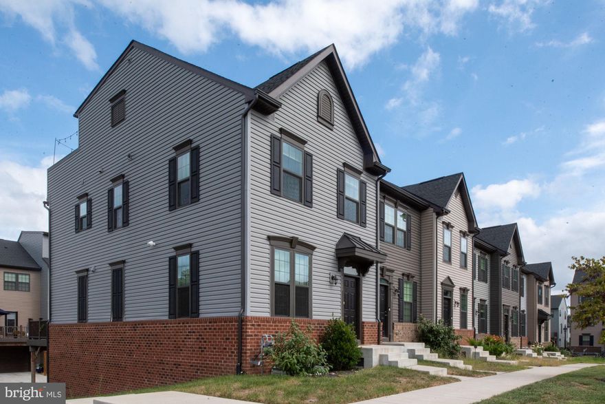 Discover this exceptional townhome in Fredericksburg, distinguished as the largest end-unit within the community. This residence features an expansive open-concept design distributed across four finished levels, complemented by a spacious garage. The main level includes a welcoming living room that seamlessly connects to a gourmet kitchen and dining area. The kitchen is equipped with a large island, granite countertops, stainless steel appliances, a gas range, and a pantry, making it suitable for both daily living and entertaining guests. From the dining area, residents can access a generous composite deck, ideal for outdoor gatherings and leisure activities. The first upper level offers a spacious primary bedroom with a walk-in closet and an en-suite bathroom featuring double sinks, a separate walk-in shower, and a soaking tub. This level also includes two additional bedrooms, a full bathroom, and a laundry area. The second upper level presents a versatile space with a built-in bar, a full bathroom, and access to a rooftop terrace, perfect for relaxation or hosting social events. The lower level comprises a family room, additional storage options, and an attached garage, enhancing the home's overall functionality. Conveniently situated near the VRE station, shopping centers, restaurants, and Interstate 95, this property offers a combination of modern amenities and practical design.