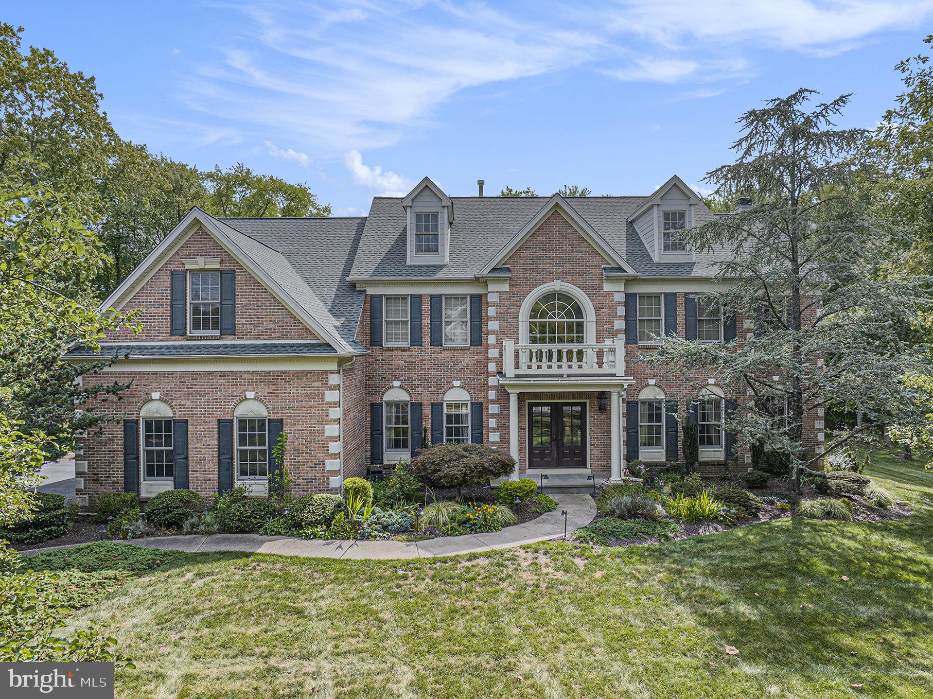 Welcome to a masterpiece of timeless elegance that is 1150 Walnut Farm Rd, an absolutely stunning, expansive brick front colonial with Hardie siding (NO stucco) nestled on over one acre of beautifully wooded Lower Gwynedd grounds. Recent updates add both peace of mind and efficiency, including a new roof within the last year and fully owned solar panels that keep expenses low. Immediately, you'll notice the stately appeal with its arched windows and Juliet balcony above the grand double front doors. Step inside the sprawling two-story foyer to be greeted by an elegant curved stairway. To the right, a formal sitting room and conveniently located home office; to the left, a refined dining room adjacent to what any chef would deem a dream kitchen, featuring a six-burner gas stove, center island with bar seating, stainless steel appliances and abundant cabinetry. A breakfast room flanks the kitchen, offering views of the serene backyard through elegant Palladian windows. Continuing, step down into the expansive family room with a wood-burning fireplace framed by built-ins and three arched windows that flood the space with daylight. A convenient laundry room, mudroom, and half bath complete the first floor. Ascend the back staircase from the kitchen to discover three well-appointed bedrooms, two sharing a full bath. Down the hall sits a guest bedroom with an ensuite bath, while the massive primary suite boasts two walk-in closets, a sitting room, and a spa-like bath with soaking tub, dual vanities, stall shower and skylight. But wait—there’s more! The finished lower level provides a versatile second family room, game room, media room, or au pair, teen or in-law suite with its own bedroom and full bath, plus additional unfinished space for storage. Outside, you’ll feel like you're at your own private resort: a cozy deck leads to a sprawling, multi-level patio surrounding a tranquil in-ground pool, outdoor kitchen, firepit area, and an already established fenced-in garden with strawberries and tomatoes. All of this is fully fenced and backs onto township-owned wooded lands for maximum privacy. This home offers serene country-style living with many nearby conveniences including Trader Joe’s, popular restaurants, vibrant downtown Ambler, boutique shops, arts and annual festivals and easy access to major roadways including direct SEPTA regional rail service into Center City. With timeless architecture, abundant space, and a backyard oasis, this estate offers the perfect retreat to call your own.