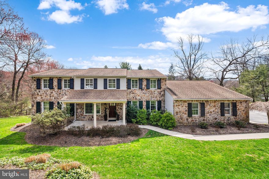 Boasting upgrades and custom finishes galore, this impeccably maintained stone colonial is set back a pleasing distance from the road on a tranquil cul-de-sac, on a leafy, tree-lined lot. A driveway gracefully winds down to the side of the home; from there, a walkway leads to a covered front porch with ample room for chairs and a bistro table. Step inside and admire the many enhancements throughout, including exquisite Brazilian cherry floors, new Pella windows with plantation shutters, neutral paint, recessed lighting and solid-wood paneled doors. Just off the gracious foyer sits a sunny dining room with custom moldings and upgraded light fixture. Paneled doors swing open to reveal a renovated, eat-in chef’s kitchen with slate floor, island seating, plentiful storage (including a pantry closet), new stainless-steel appliances, sparkling white cabinetry and direct access to the attached two-car garage. The kitchen overlooks a warm and welcoming family room with gas fireplace, stone accent wall and wrap-around built-ins. Full-panel glass doors—adorned with custom plantation shutters—open to a Timber Tech® deck that spans the entire width of the home and offers abundant room for lounging and dining al fresco. A renovated powder room, laundry room and spacious, light-filled front living room complete this amenity-rich first floor. The cherry wood floors continue upstairs, where you’ll find a soothing primary suite with walk-in closet and upgraded ensuite full bath. Down the hall sit three spacious secondary bedrooms, plus a large, renovated hallway bath with frameless glass shower door and double vanity nestled in a custom arched alcove. The walk-out lower level includes an open area for entertaining and play, full bath, sauna, storage room and space for a home gym if desired. There’s also access to a patio that overlooks the home’s sprawling grounds. For safety and low-maintenance living, this property boasts a whole-house generator, newer roof & systems. Homes on this scenic cul-de-sac sit mere minutes from popular Main Line destinations, including downtown Wayne, King of Prussia Mall & Town Center, Valley Forge National Park and public transit. Make plans to tour this turnkey charmer today!