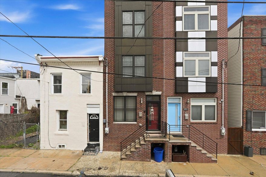 Welcome to 2207 E Oakdale Street — a meticulously maintained, three-story brick rowhome that delivers the space, finishes, and flex-living options rarely found at this price point. Spanning four finished levels including a fully finished basement, this home offers exceptional versatility for today's buyers.
The main level opens into a bright, open-concept living and dining area anchored by warm hardwood floors, recessed lighting, and crown molding throughout. The layout flows seamlessly toward a truly standout kitchen featuring rich espresso cabinetry, granite countertops, a large center island with seating, subway tile backsplash, stainless steel appliances, and pendant lighting — a setup that functions as the natural hub of the home. A rear door off the kitchen leads directly to the private backyard patio.
The fully fenced backyard is a quiet retreat, complete with a poured concrete patio, mature shade trees, privacy fencing with decorative planter accents, and a dedicated area for grilling. 
Upstairs, the second floor features a generously sized secondary bedroom, an additional bedroom or home office with great natural light, a full hallway bath, and a convenient second-floor laundry closet with a stacked washer/dryer — no hauling laundry up and down stairs. The third floor is dedicated entirely to the primary suite, which impresses with a tray ceiling, crown molding, recessed lighting, and dual windows bringing in natural light. The ensuite bath offers a double vanity with dark granite, an oversized tiled glass-enclosed shower, and tile flooring.
The bonus? A tucked-away wet bar/kitchenette nook with cabinetry and granite on the upper stair landing — a perfect setup for a coffee bar, home bar, or entertainment station. Just steps away, access the private rooftop deck with sweeping views of the Philadelphia skyline!
The finished basement adds a full additional living level, with tile floors, recessed lighting, a full bath — ideal as a media room, playroom, gym, or guest suite.
This home checks every box, make sure to book your showing today!